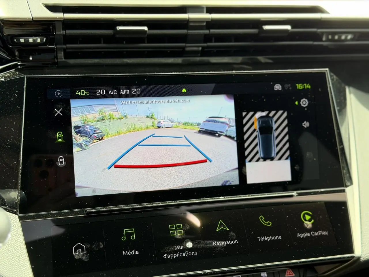Écran tactile intérieur montrant la caméra de recul et l’aide au stationnement du Peugeot 308 blanc Okenite.