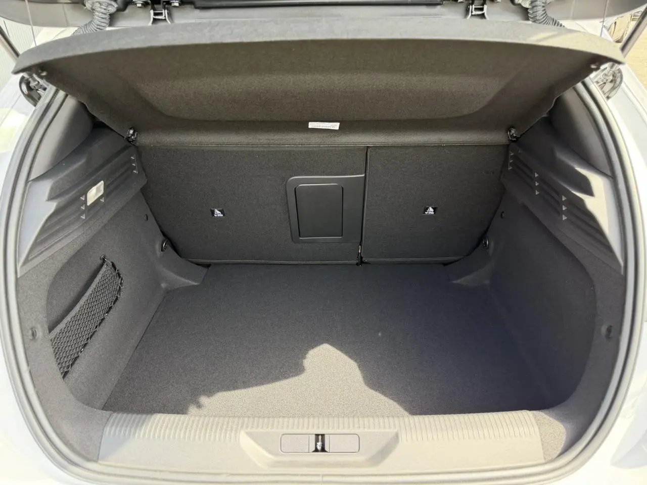Coffre ouvert vu de l'arrière d'une Peugeot 308 blanc Okenite, espace de chargement propre et bien agencé.