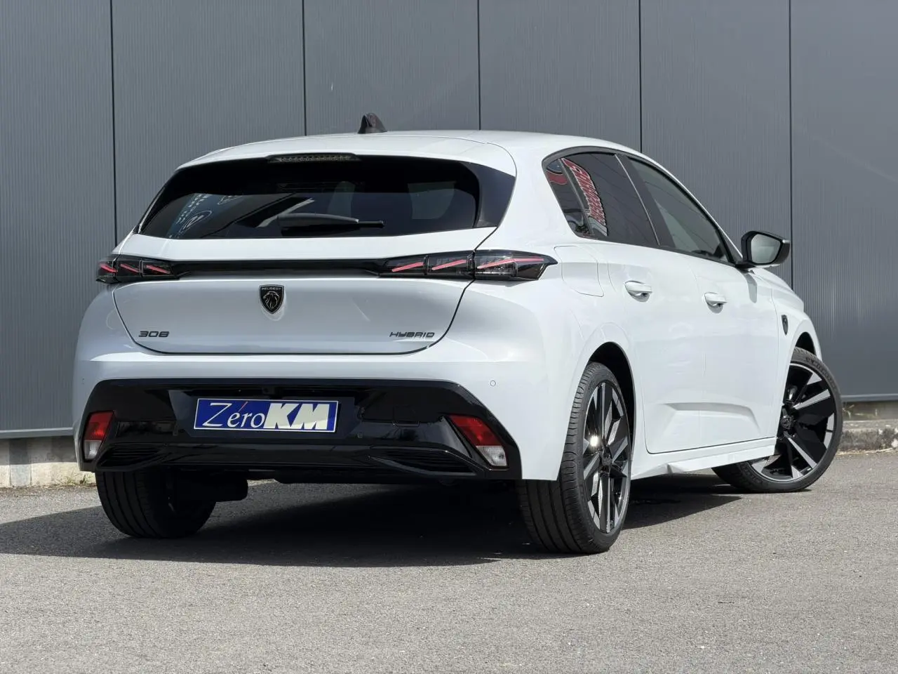 Vue 3/4 arrière droite d'une Peugeot 308 blanche Okenite avec jantes alliage bi-tons et feux arrière LED 3 griffes.