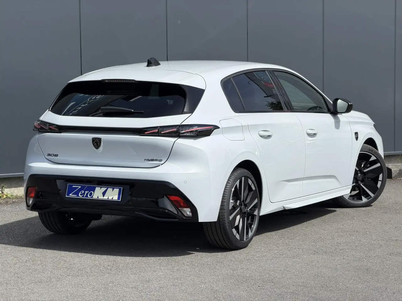 Vue 3/4 arrière droite d'une Peugeot 308 blanche Okenite avec jantes bi-tons et feux arrière à LED 3 griffes.