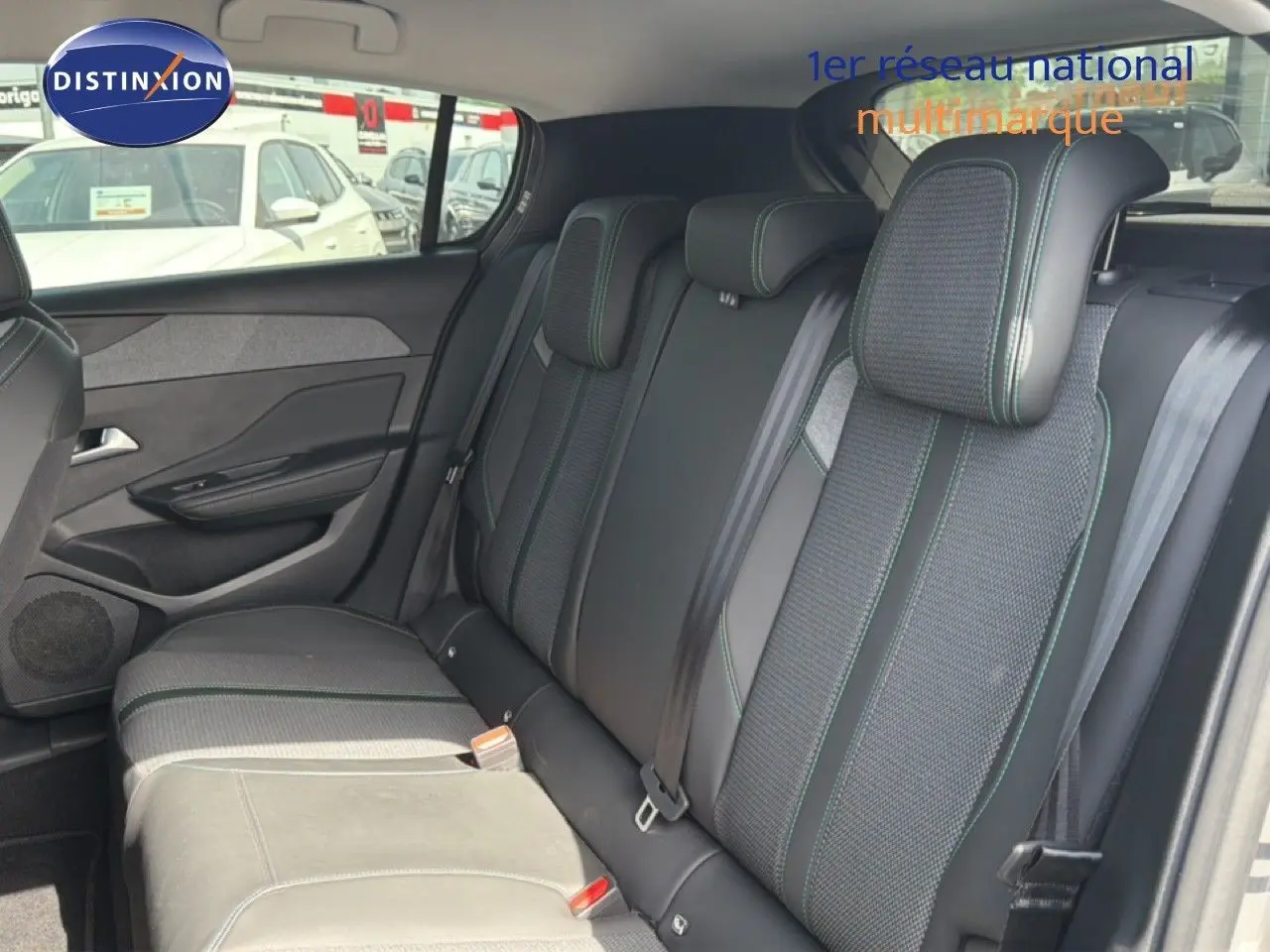 Vue intérieure arrière des sièges arrière en tissu noir avec surpiqûres vertes d'une Peugeot 308 Allure Hybrid 2025 gris Selenium Metal.