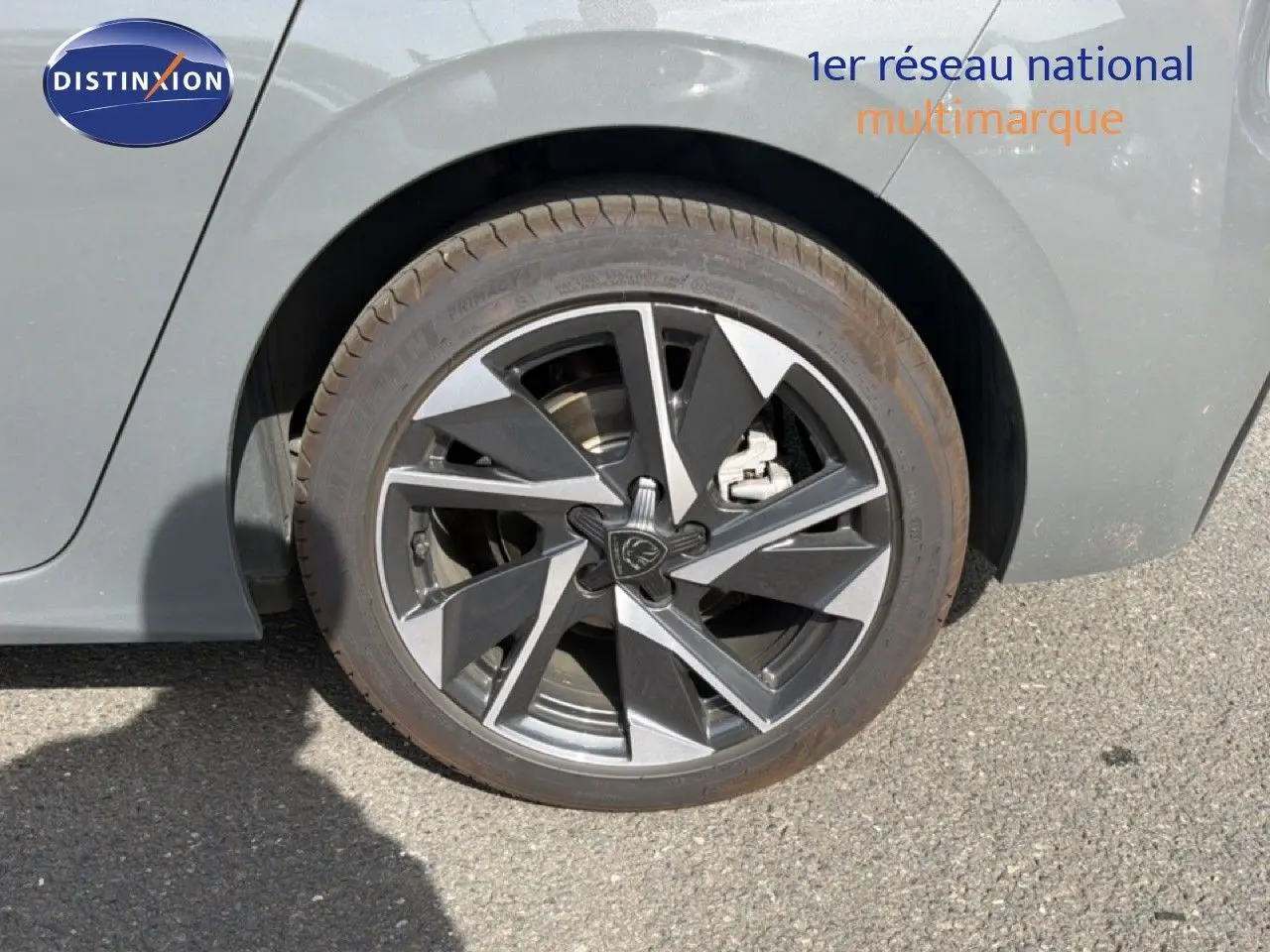 Gros plan sur la roue arrière droite d'une Peugeot 308 Allure Hybrid 145 gris selenium metal, jante alliage bicolore.