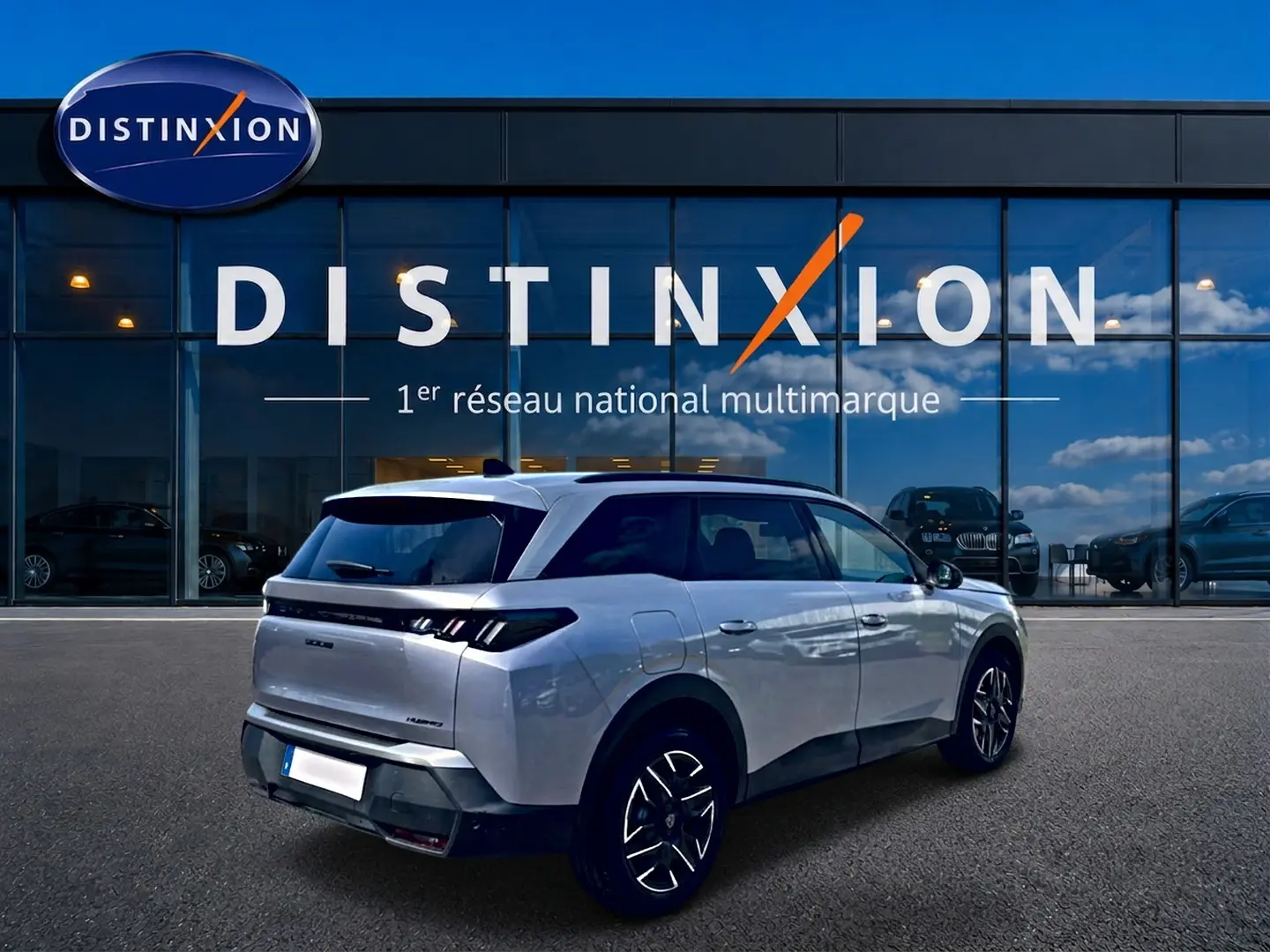 Peugeot 5008 Hybrid 145 allure e-dcs6 gris artense en 3/4 arrière droit devant une vitrine Distinxion.
