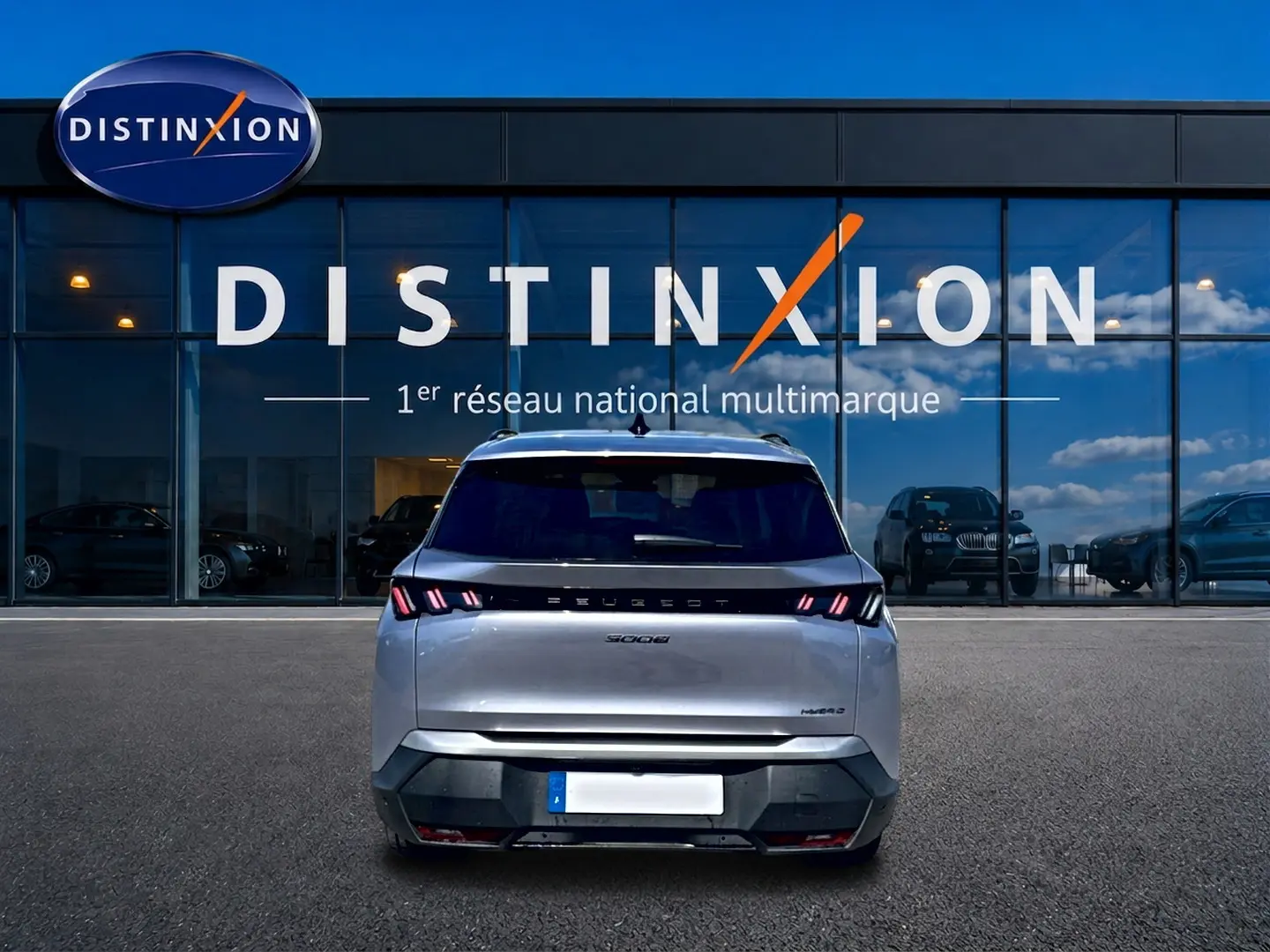 Vue arrière d’un Peugeot 5008 gris artense 2025 avec feux arrière LED et logo distinctif sur fond de vitrine Distinxion.