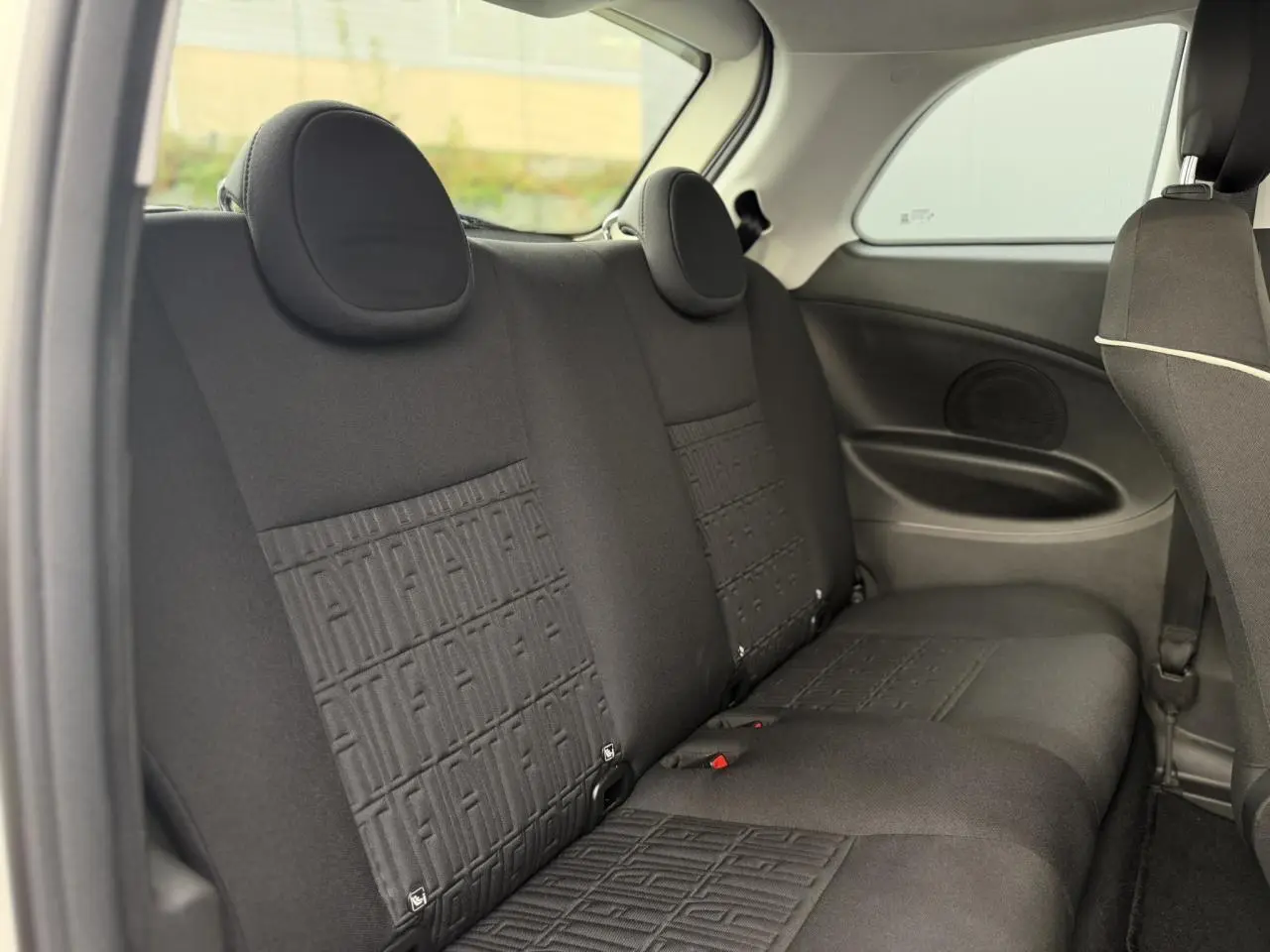 Vue intérieure des sièges arrière noirs de la FIAT 500 électrique 2024, avec motifs FIAT embossés sur les dossiers.