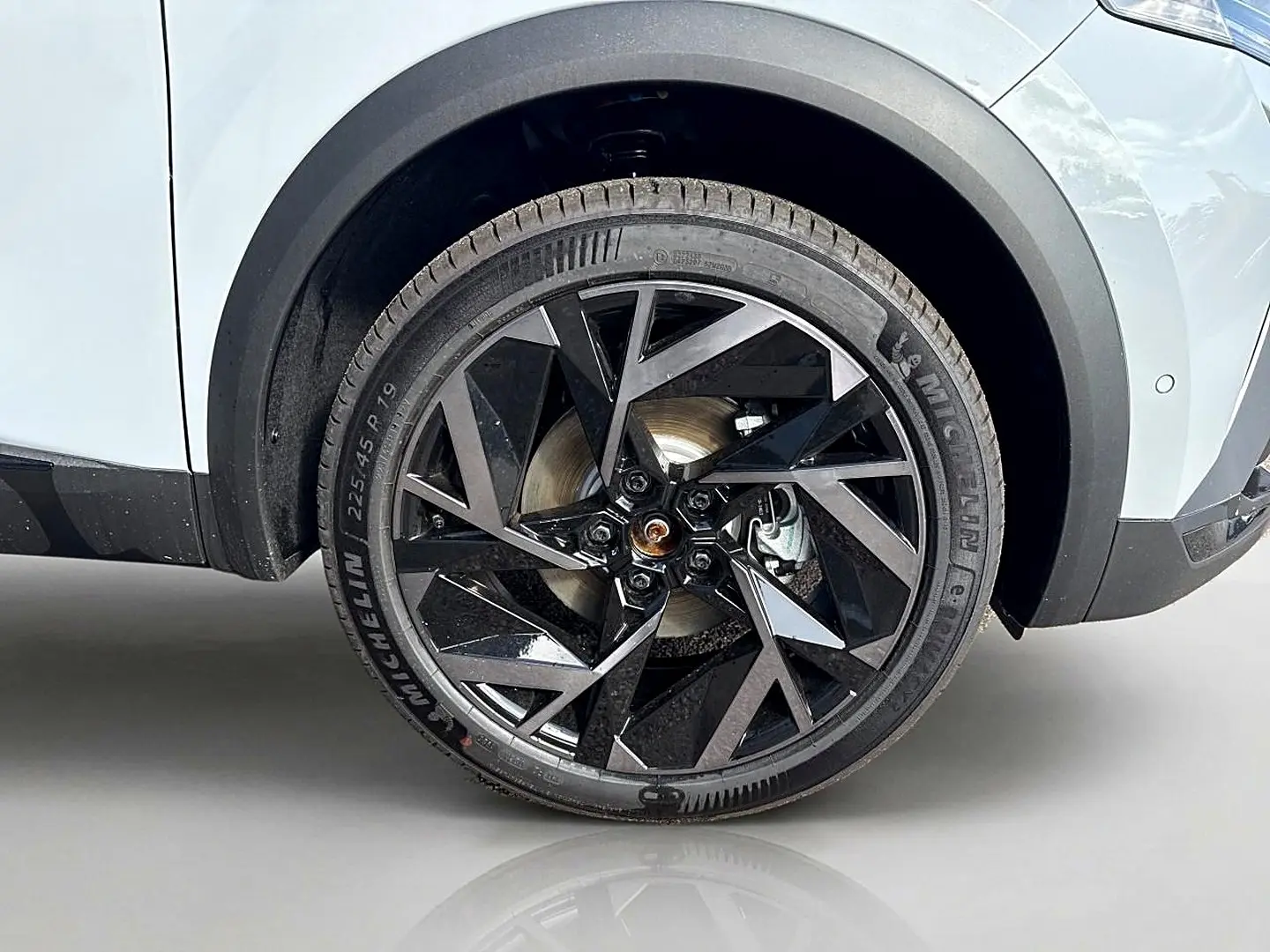 Gros plan sur la roue avant droite avec jante noire et grise du Renault Symbioz gris rafale, partie basse de la carrosserie visible.