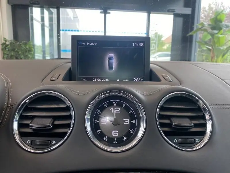 Tableau de bord gris du Peugeot RCZ 2010 avec horloge centrale ronde et écran multimédia en position relevée