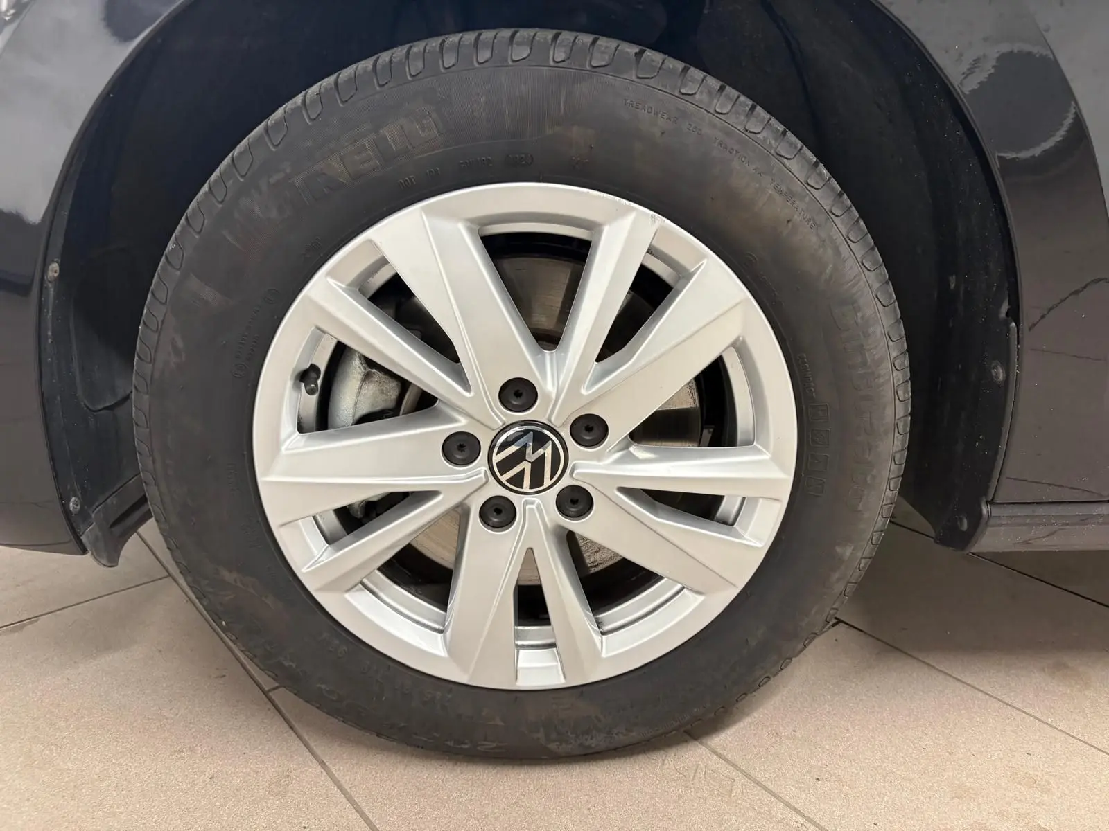 Gros plan sur la roue avant gauche du Volkswagen Touran noir intense nacré, avec jante alliage à 10 branches fines.