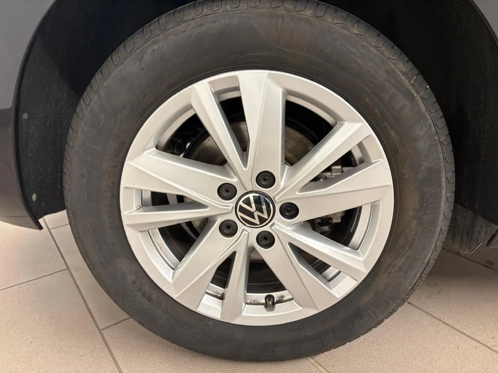 Gros plan sur la jante alliage argentée du Volkswagen Touran Noir Intense nacré, roue avant droite visible.