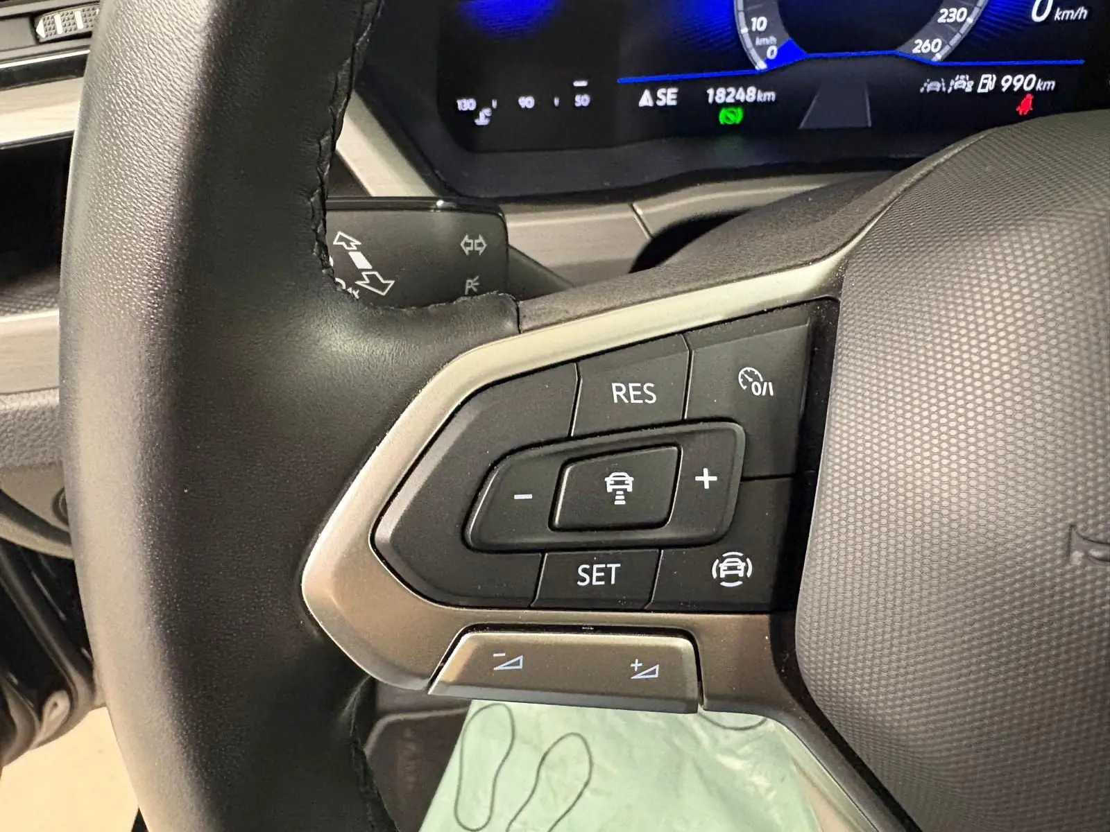 Gros plan sur les commandes au volant du Volkswagen Touran 2024 noir intense nacré, affichage digital en arrière-plan.