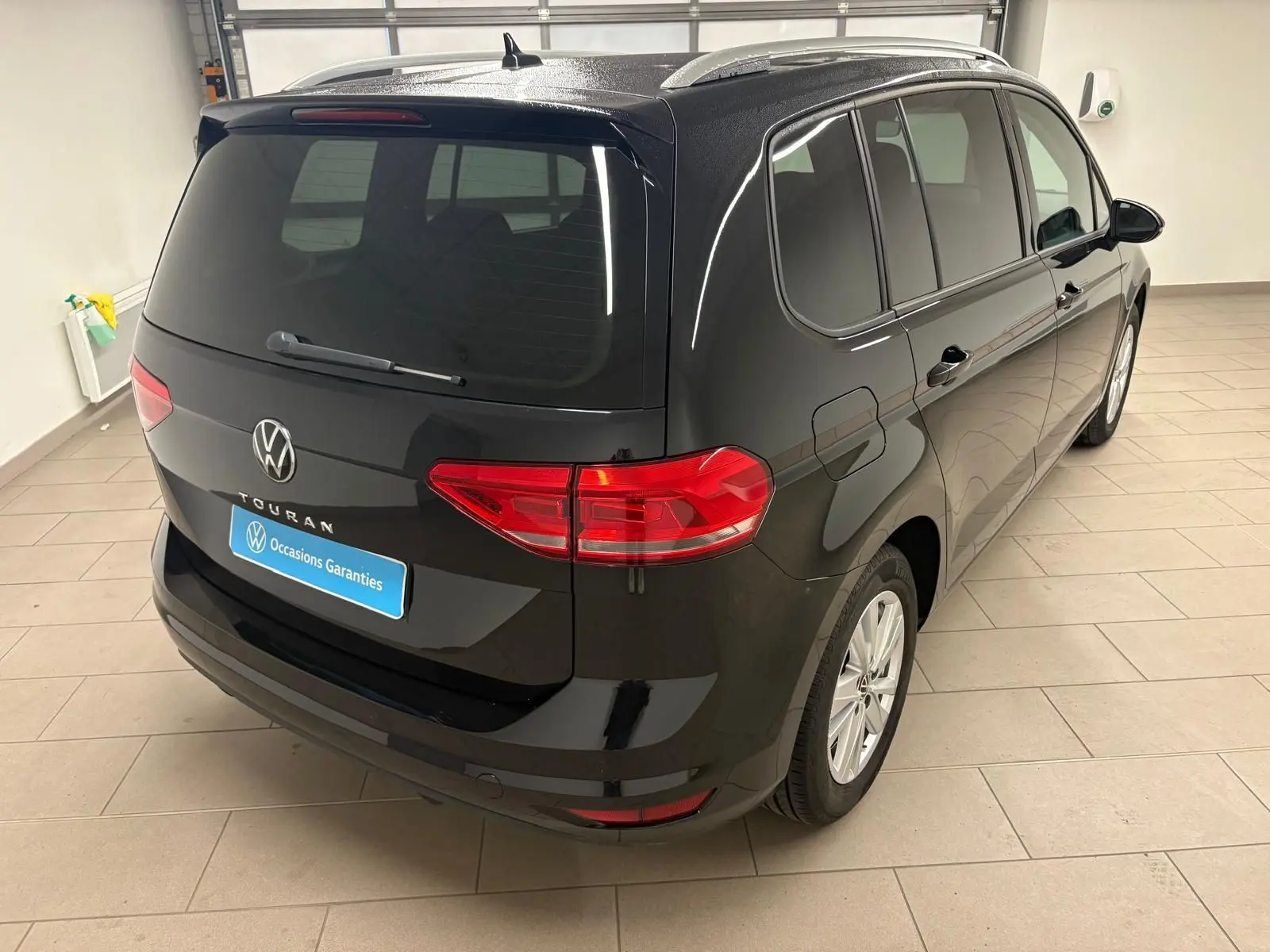 Vue 3/4 arrière droite du Volkswagen Touran noir intense nacré, soulignant son hayon électrique et vitres teintées.