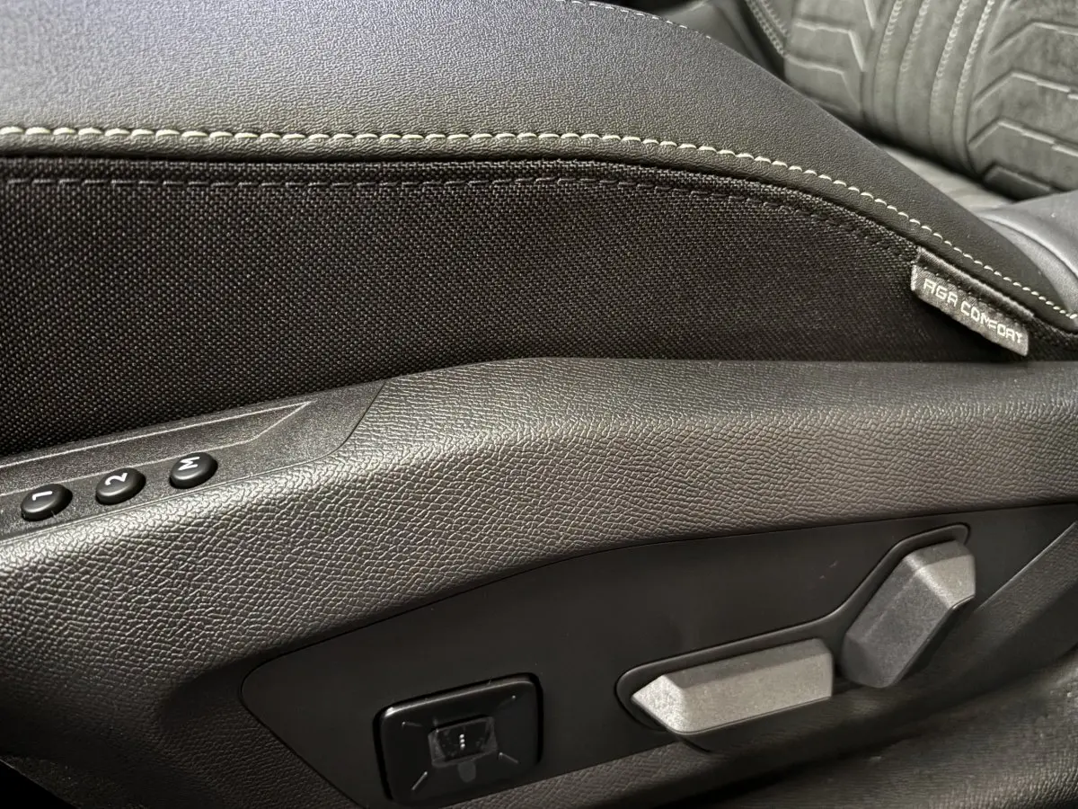 Détail des commandes de réglage électrique du siège avant noir du Peugeot 3008 hybride 2025.