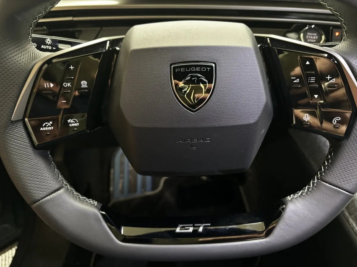 Vue rapprochée du volant cuir noir du Peugeot 3008 1.2 Hybrid 145 GT avec logo et commandes multifonctions.