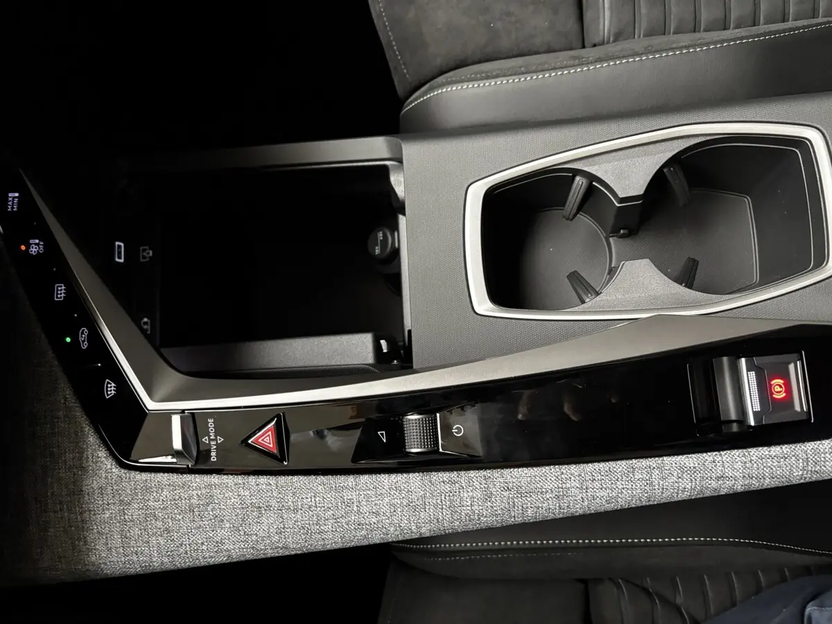 Détail de la console centrale grise avec commandes tactiles et porte-gobelets du Peugeot 3008 hybride 2025.