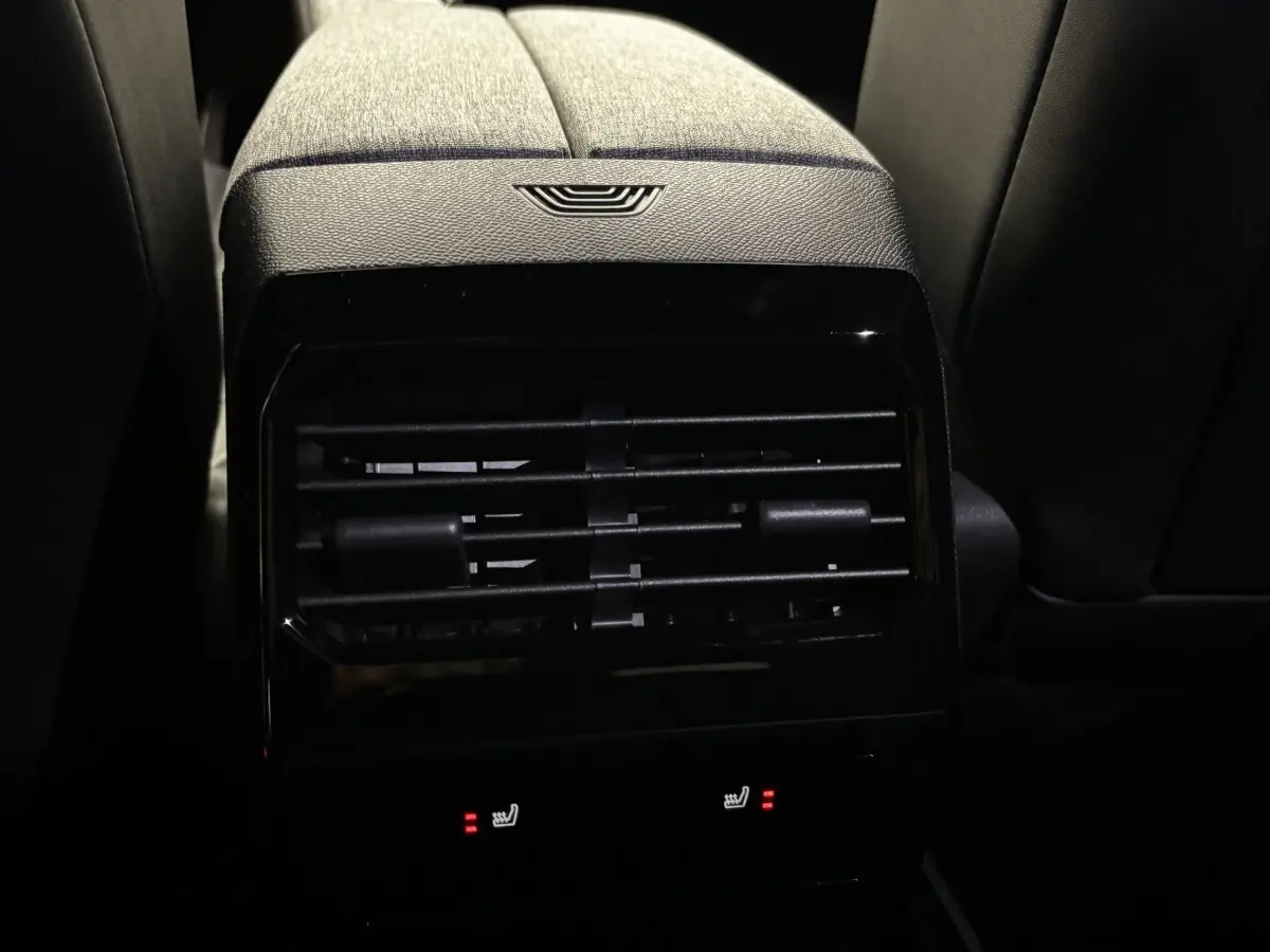 Vue rapprochée de la ventilation arrière et des commandes de sièges chauffants du Peugeot 3008 vert, intérieur sombre.