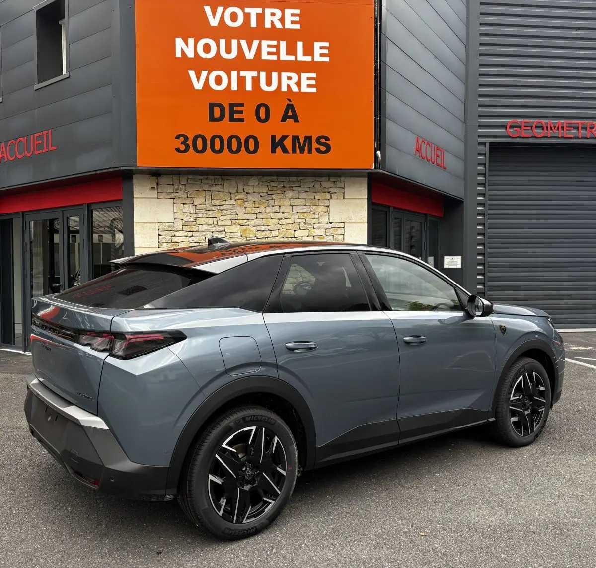 Vue 3/4 arrière droite d’un Peugeot 3008 1.2 Hybrid 145 GT gris métallisé avec toit noir et jantes noires.