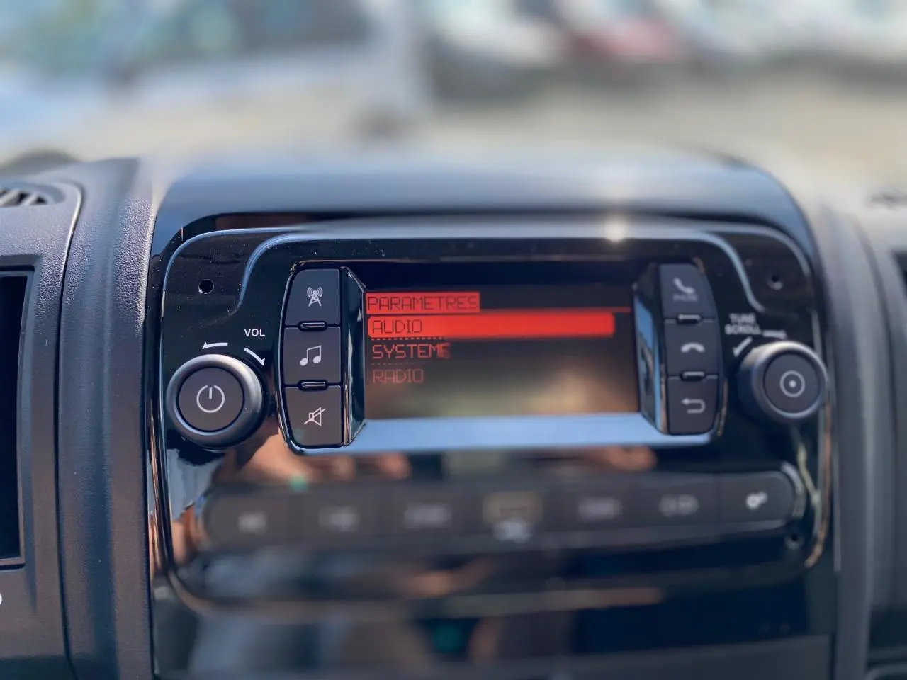Gros plan sur la console centrale du Citroën Jumper 2023, écran audio avec menu en rouge et boutons noirs.