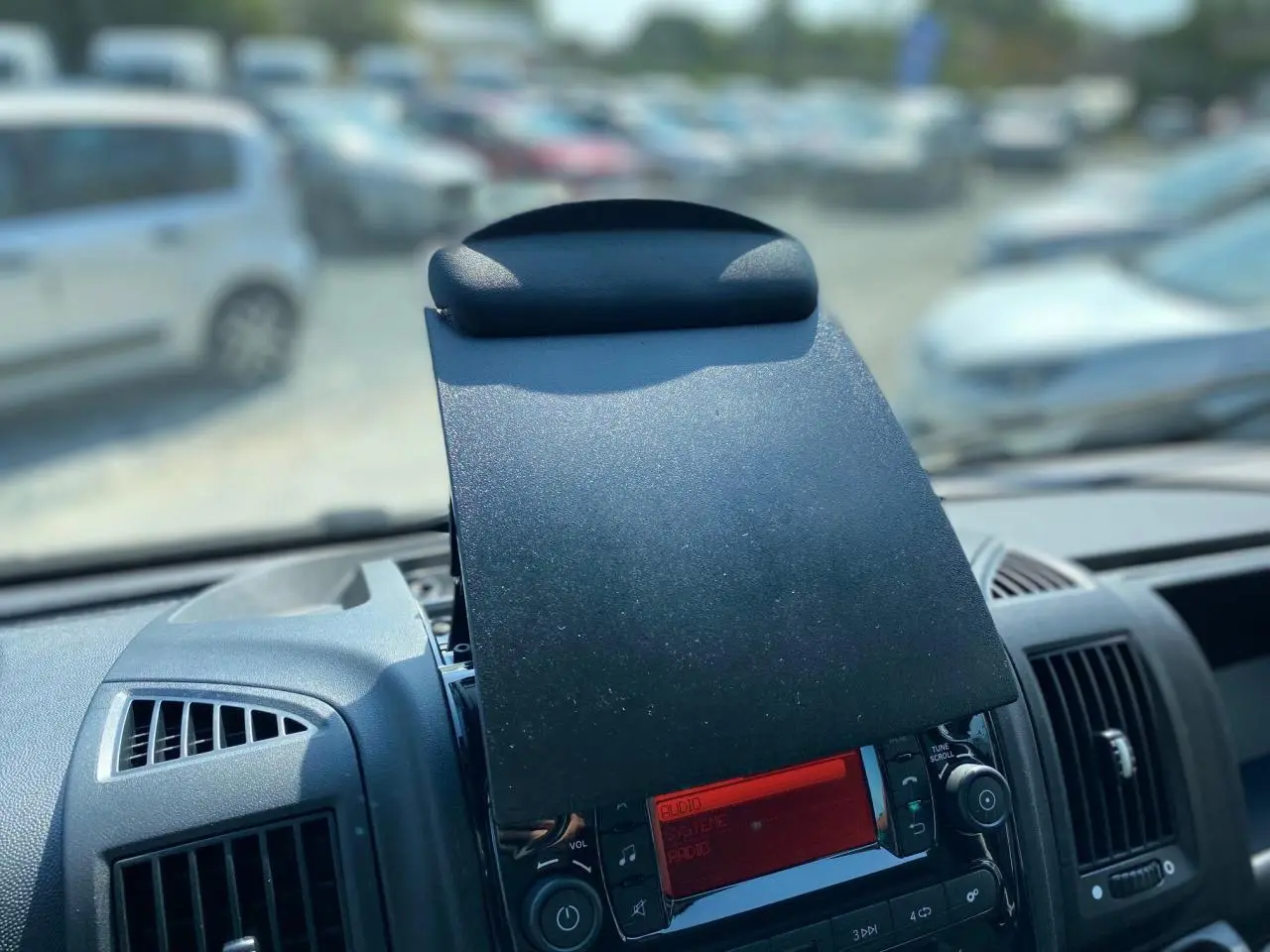 Vue rapprochée de la console centrale du Citroën Jumper 2023, écran radio rouge avec cache rabattable noir.
