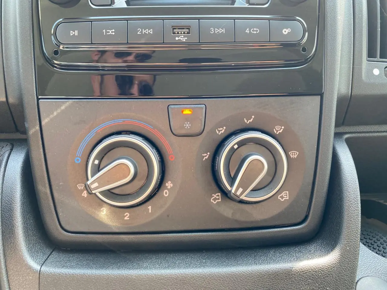 Gros plan sur la console centrale du Citroën Jumper 2023, avec commandes de climatisation manuelle et boutons multimédia.