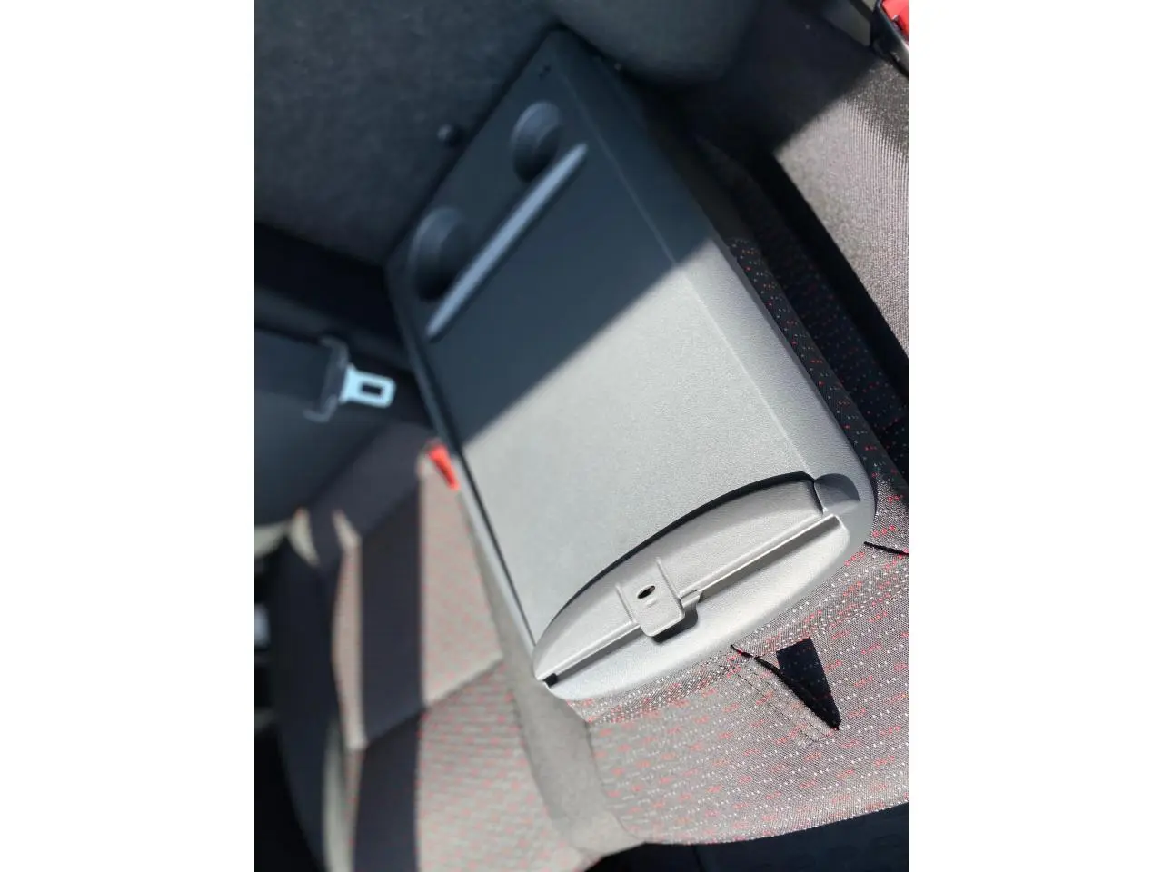 Détail de l'accoudoir central avec porte-gobelets du siège arrière du Citroën Jumper 2023, tissu gris à motifs rouges.