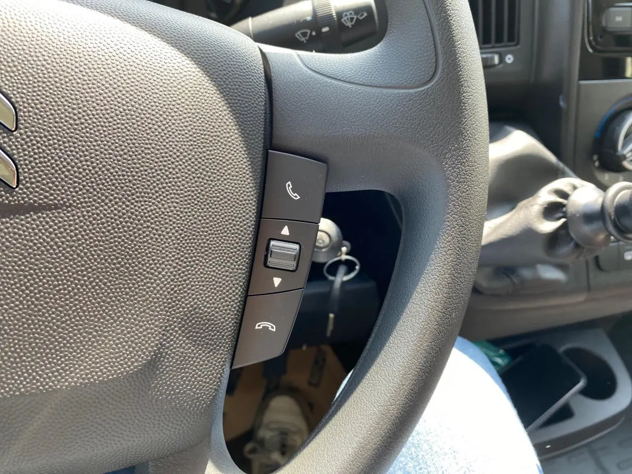 Gros plan sur le volant noir du Citroën Jumper 2023 avec commandes Bluetooth et levier de vitesse manuel visible.