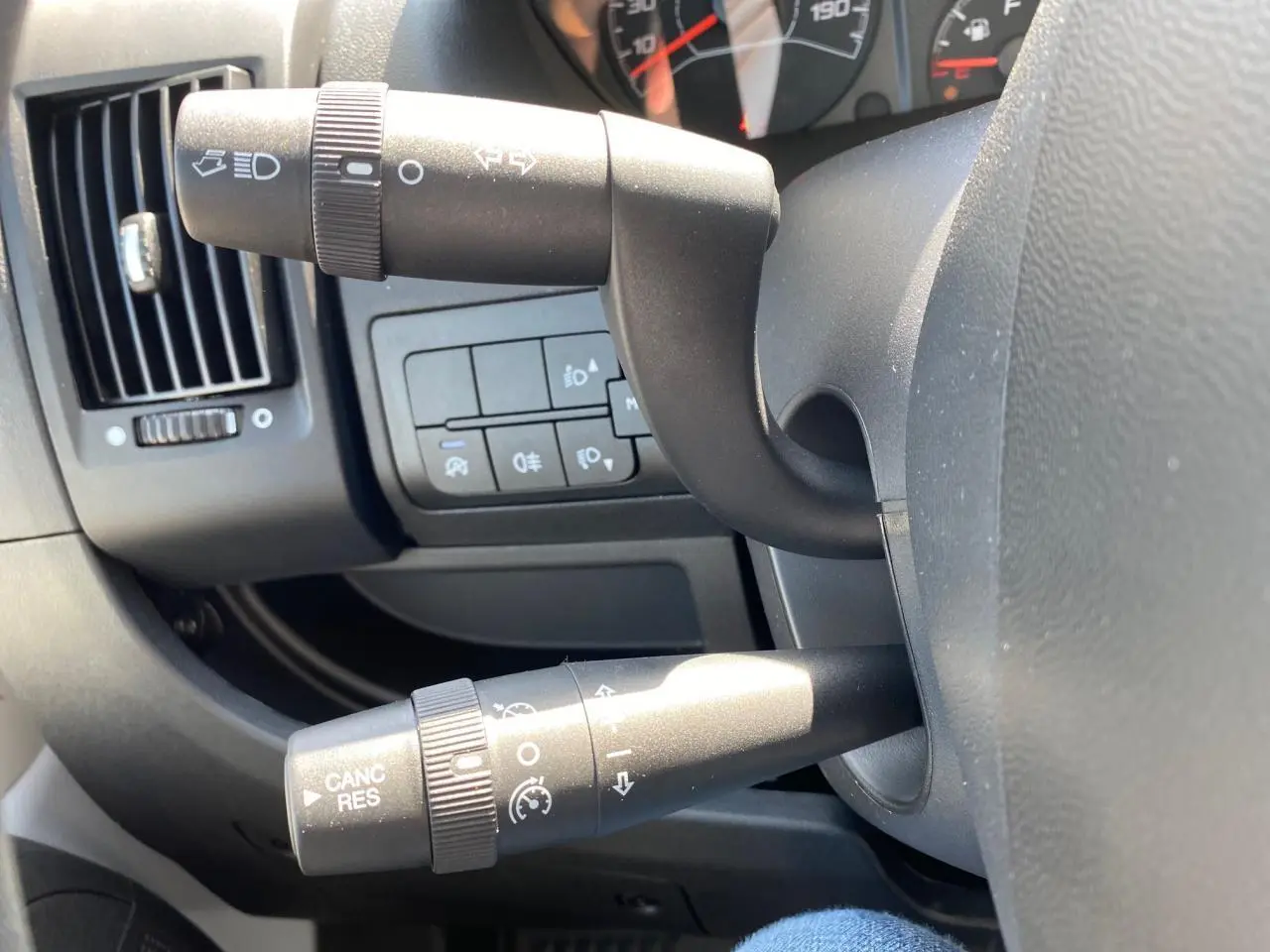 Gros plan sur les commandes au volant du Citroën Jumper 2023, avec tableau de bord et manettes noires visibles.