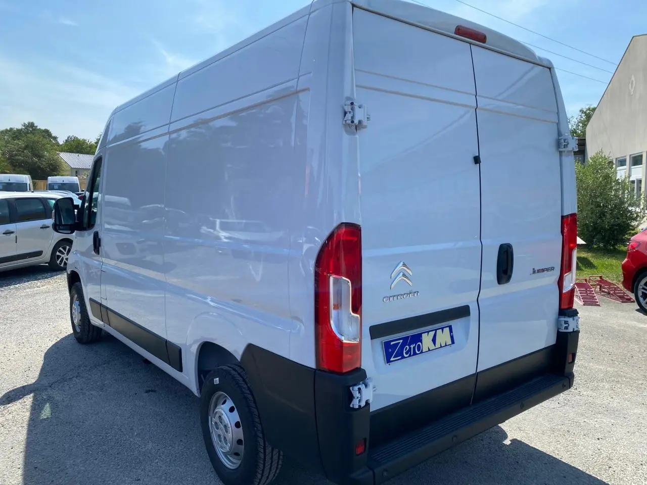 Vue 3/4 arrière droite d’un utilitaire Citroën Jumper blanc avec portes arrière tôlées ouvertes à 270°.