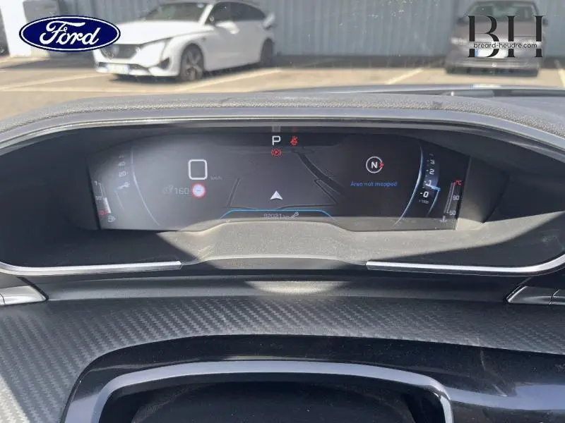 Vue rapprochée du tableau de bord numérique de la Peugeot 508 SW gris Artense avec affichage de navigation et compte-tours.