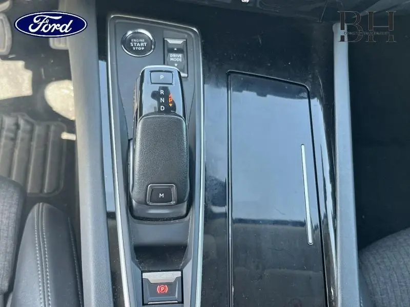 Console centrale avec levier de boîte automatique et bouton start/stop sur fond noir brillant, intérieur Ford.