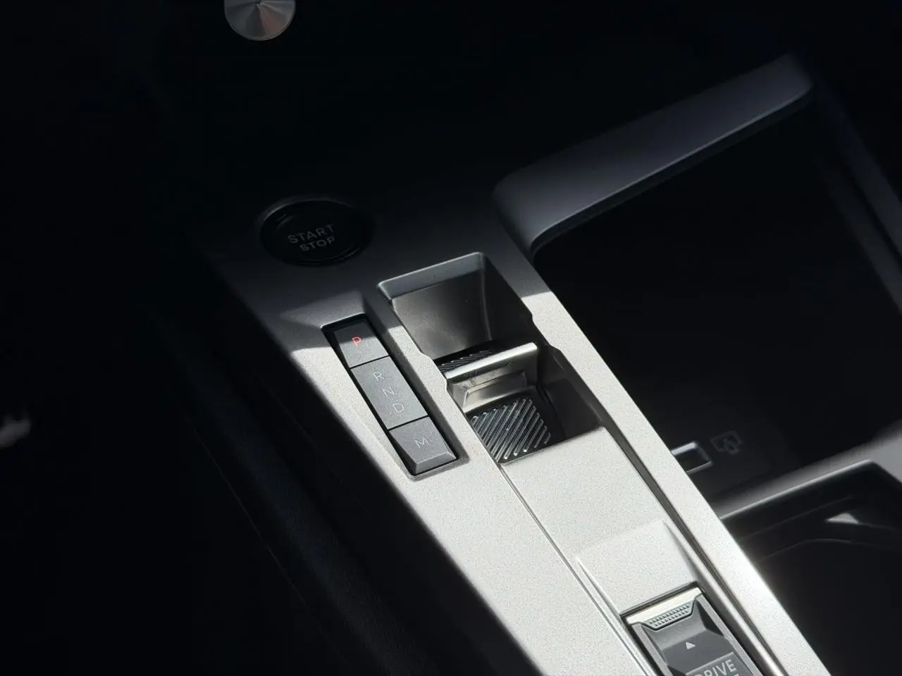 Vue rapprochée de la console centrale argentée avec sélecteur de boîte auto et bouton start/stop sur Peugeot 308 NV Hybrid 145 GT.
