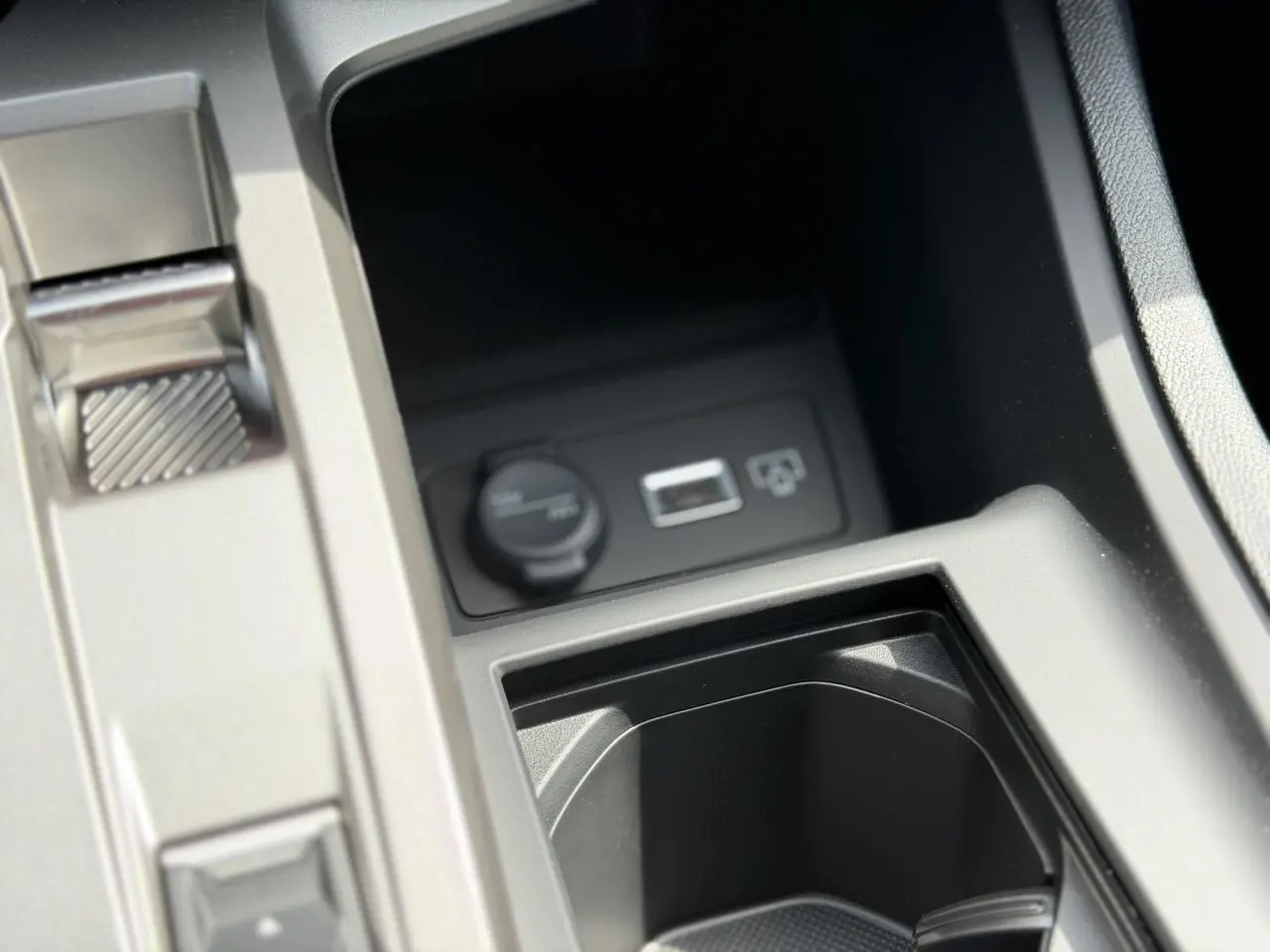 Gros plan sur la console centrale de la Peugeot 308 NV Hybrid 145 GT e-DSC6 noire, montrant prise 12V et port USB.