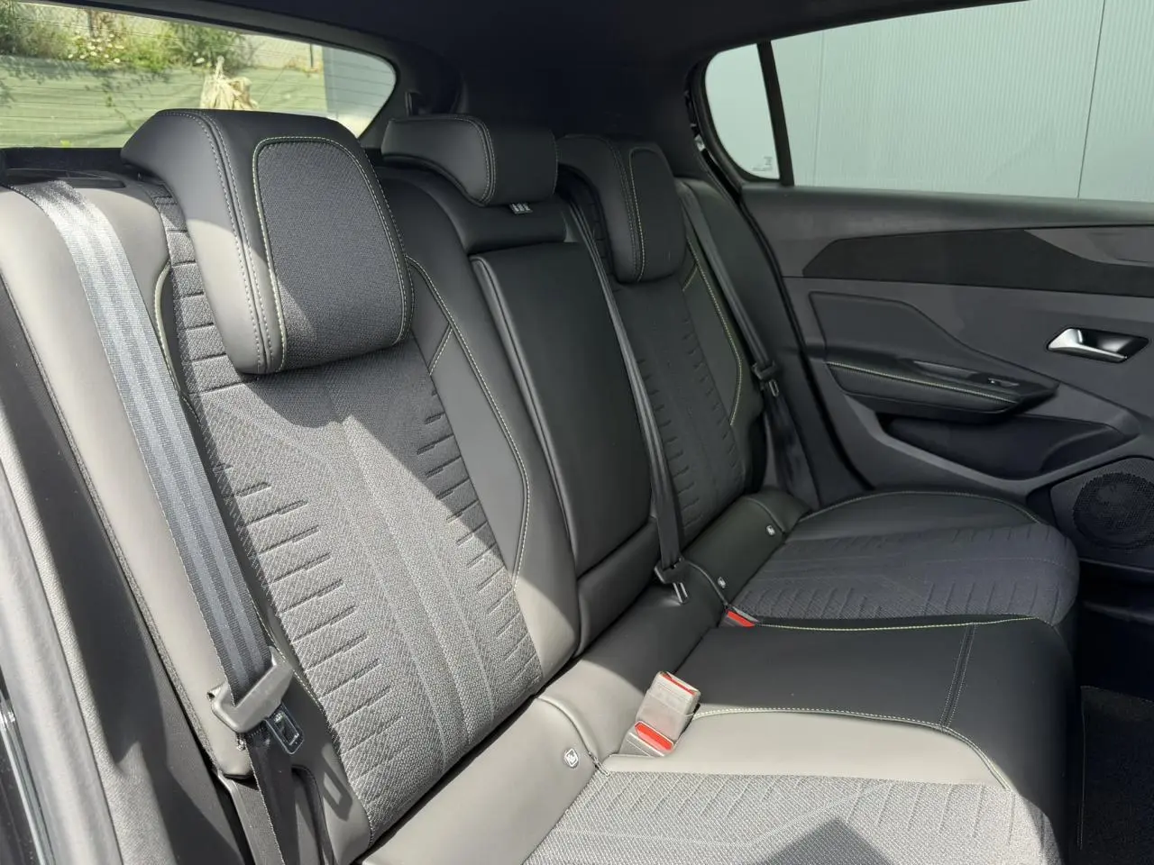 Vue intérieure côté droit des sièges arrière noirs avec surpiqûres vert Adamite de la Peugeot 308 NV Hybrid 2026.