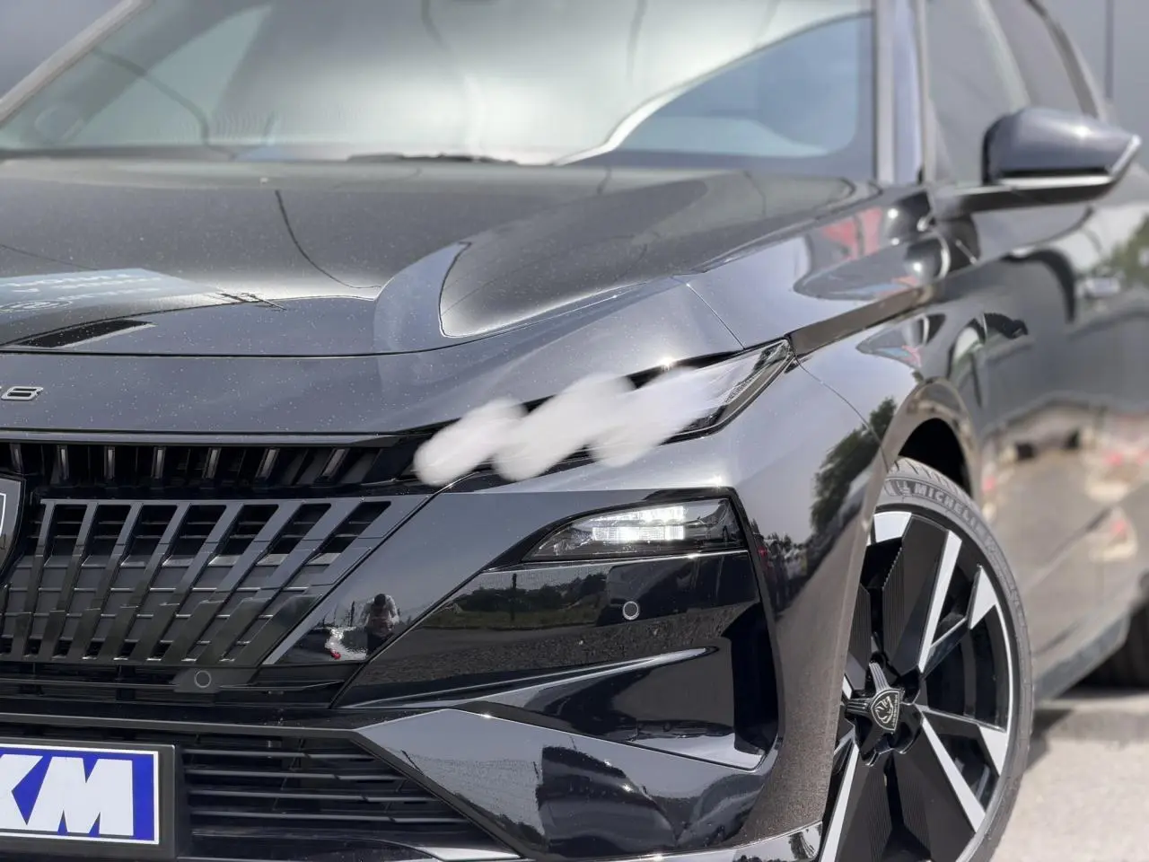 Vue 3/4 avant droit de la Peugeot 308 NV Hybrid 145 GT e-DSC6 noire Perla avec jantes alliage bi-tons et calandre distinctive.