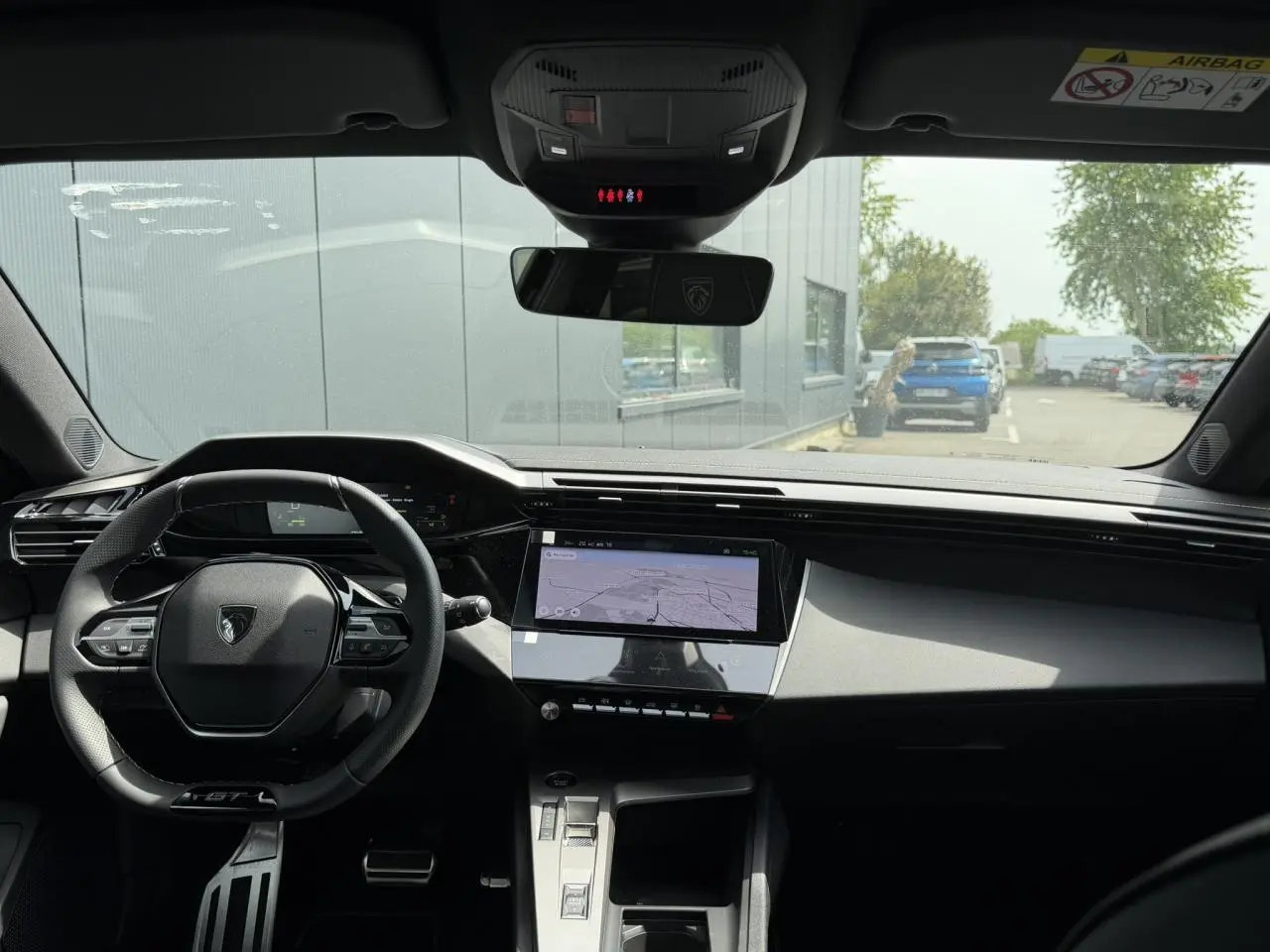 Vue intérieure avant du Peugeot 308 NV Hybrid 145 GT avec tableau de bord numérique et écran tactile central.