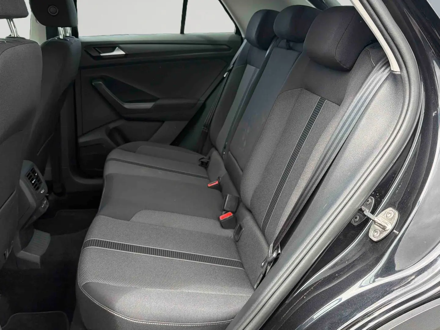 Vue intérieure côté droit sur la banquette arrière noire du Volkswagen T-Roc 2025 avec tissus et ceintures visibles.
