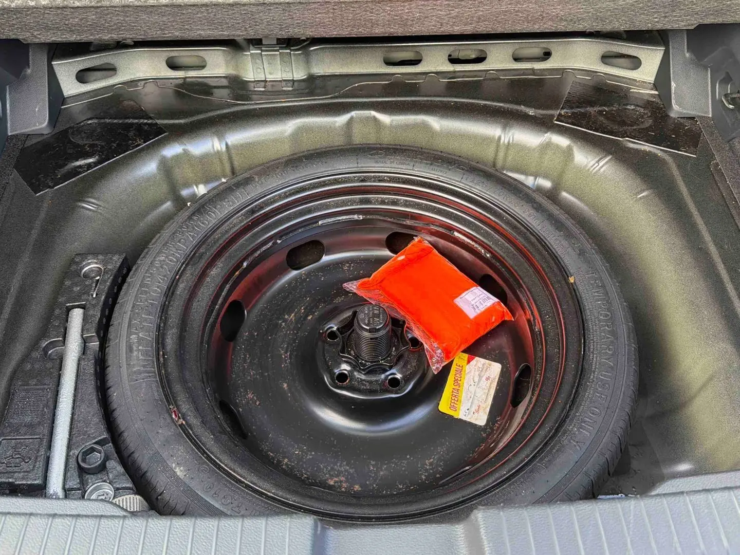 Gros plan sur la roue de secours noire dans le coffre d’un Volkswagen T-Roc 2025 avec trousse de sécurité rouge.