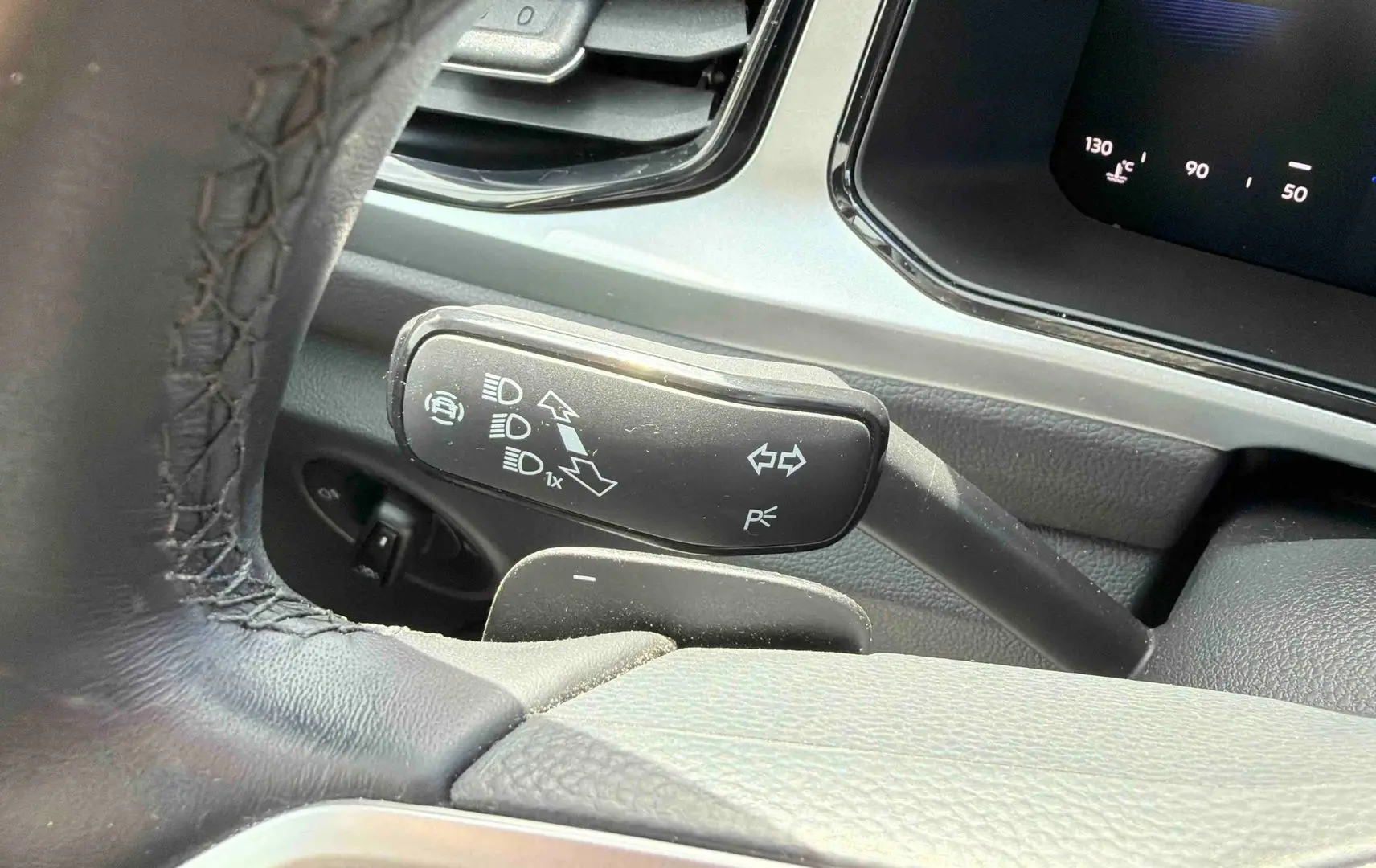 Gros plan sur la commande des clignotants et feux du Volkswagen T-Roc 2.0 TDI 150 DSG7, intérieur noir.