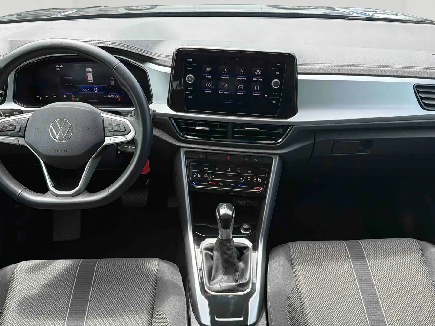 Vue intérieure avant du Volkswagen T-Roc 2025 noir, avec volant cuir multifonctions et écran tactile central.