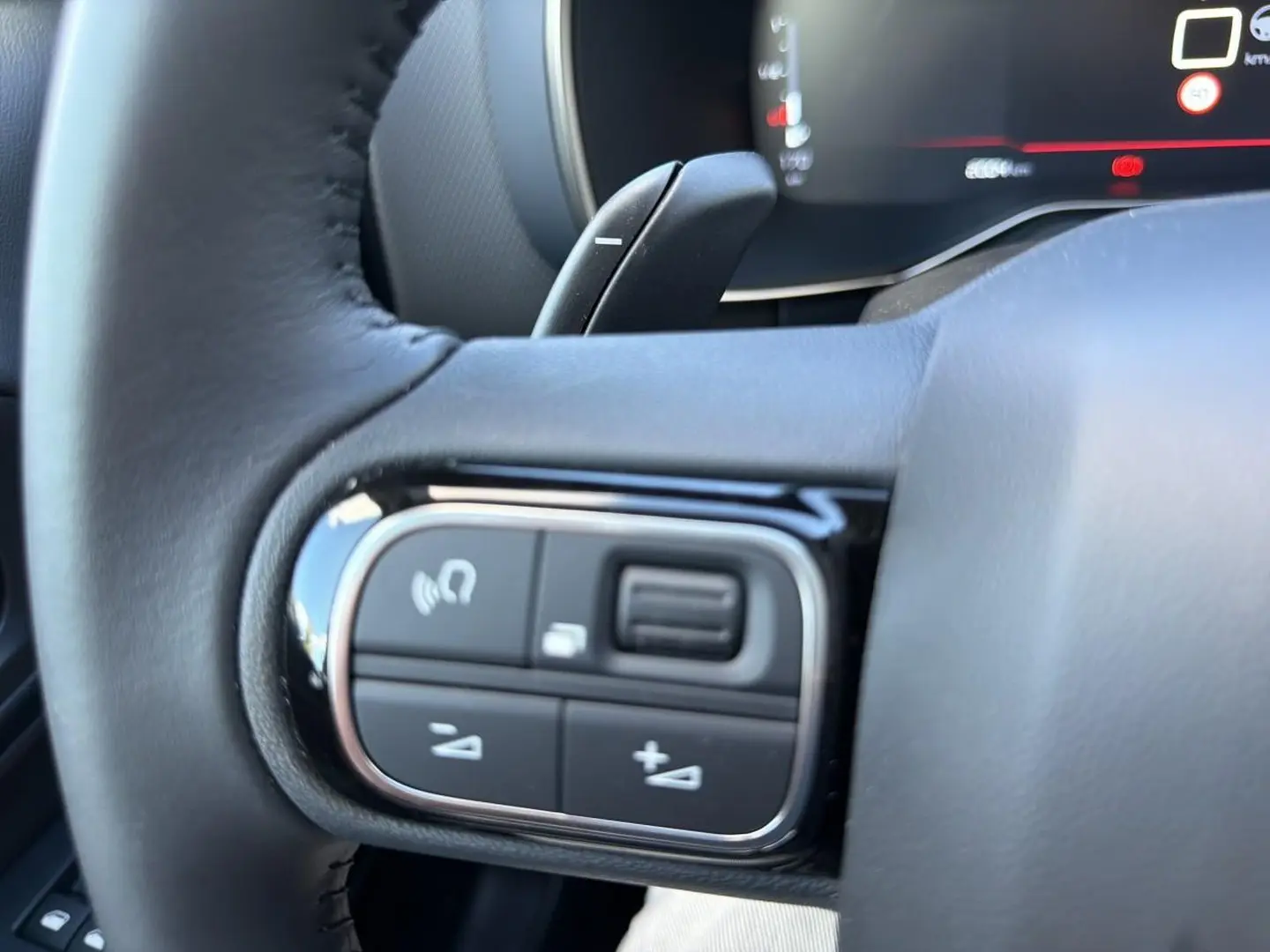 Gros plan sur les commandes multifonctions noires du volant cuir du Citroën C5 Aircross 2025, version diesel blanche.