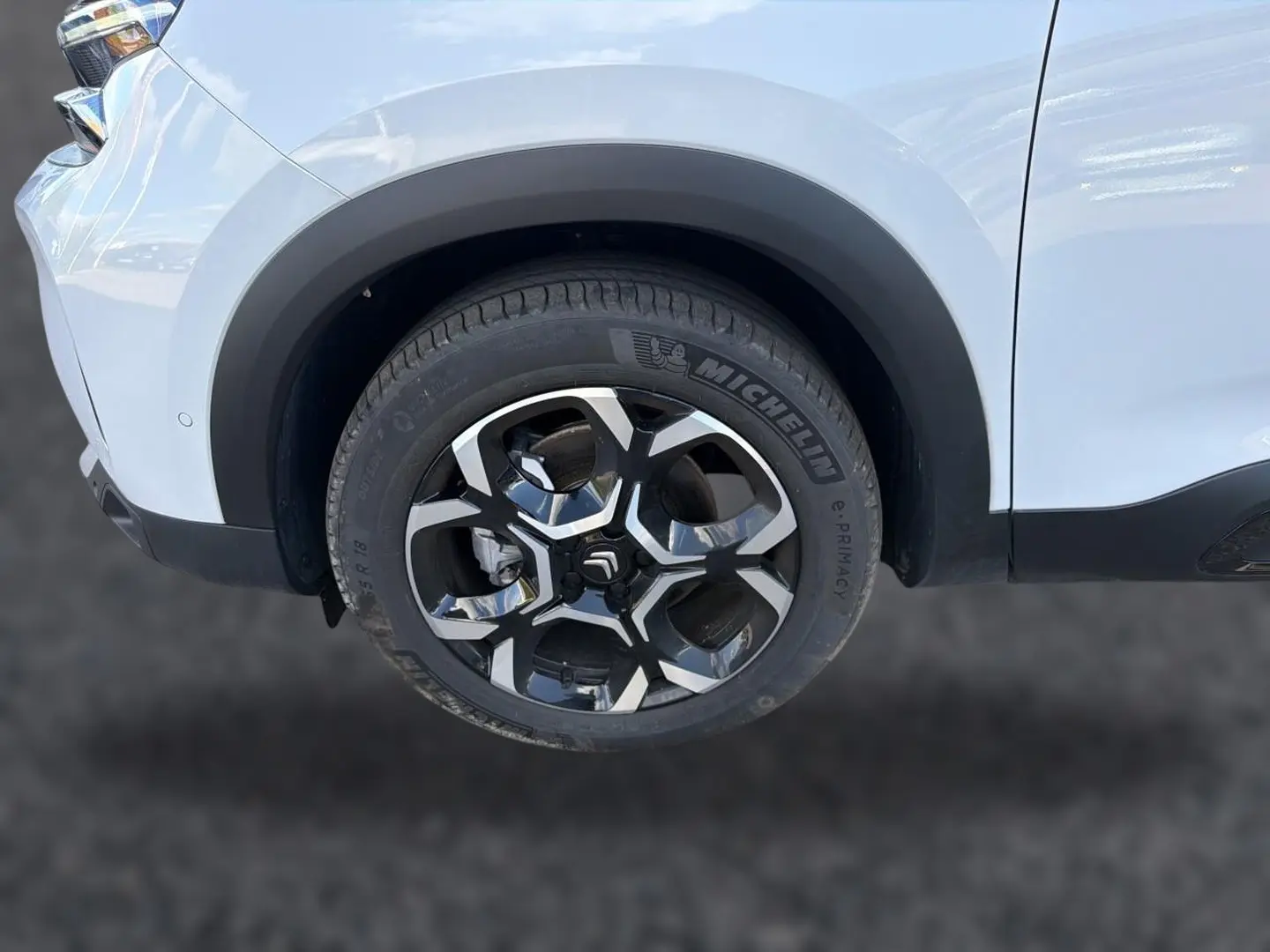 Gros plan sur la roue avant droite d’un Citroën C5 Aircross blanc avec jante alu bicolore distinctive.