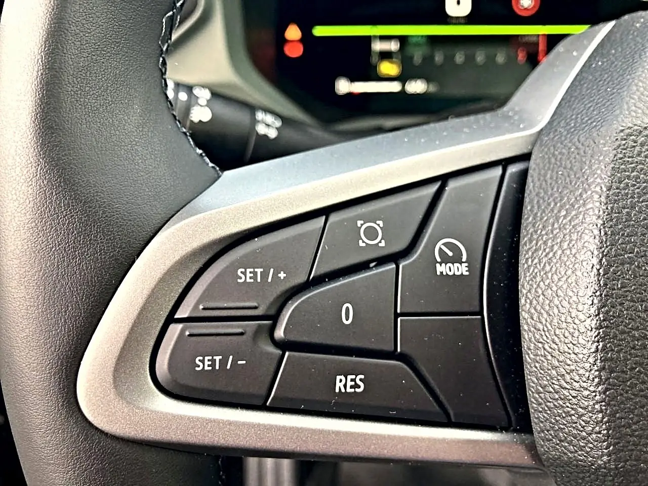 Gros plan sur les commandes multifonctions côté gauche du volant du Dacia Bigster noir, avec affichage numérique en arrière-plan.