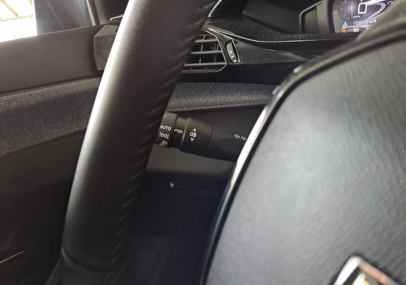 Gros plan sur le volant noir et la commande des phares de la Peugeot 308 2024 blanc Okenite.