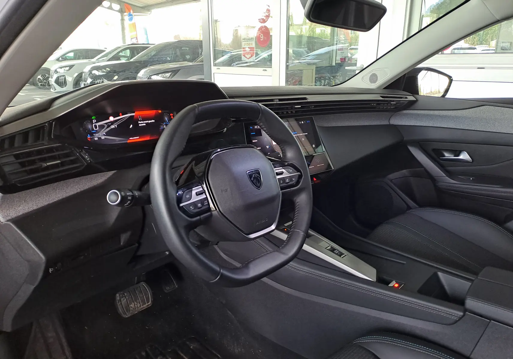 Intérieur noir de la Peugeot 308 2024, vue côté conducteur, tableau de bord numérique et volant compact multifonctions.