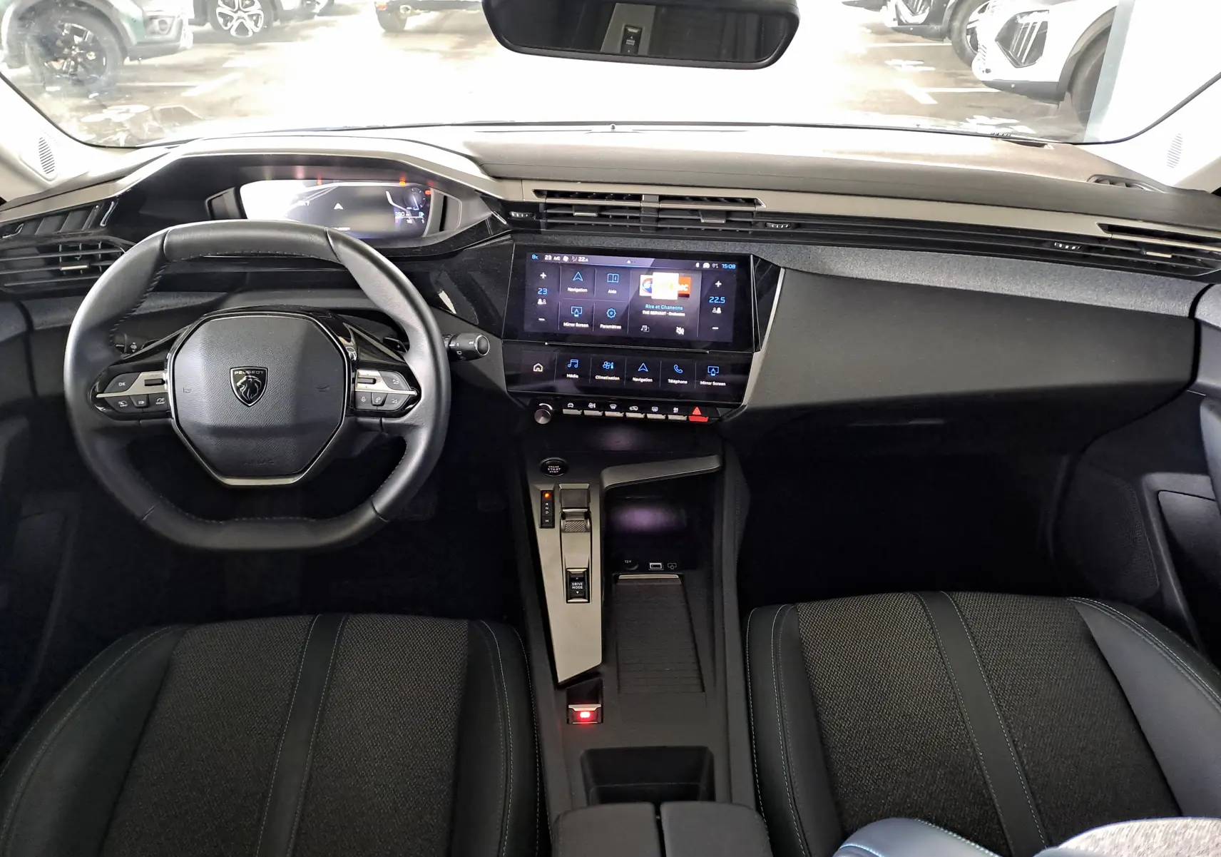 Intérieur noir de la Peugeot 308 2024, vue de face sur le tableau de bord et le volant compact au design moderne.