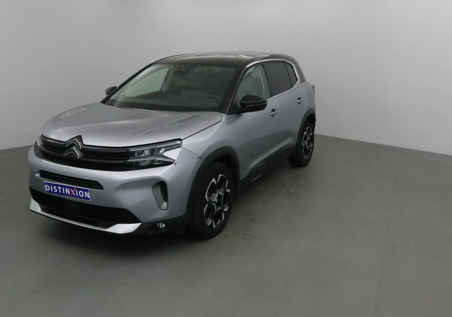 Citroën C5 Aircross gris Artense avec toit noir, vue 3/4 avant droit en intérieur neutre.