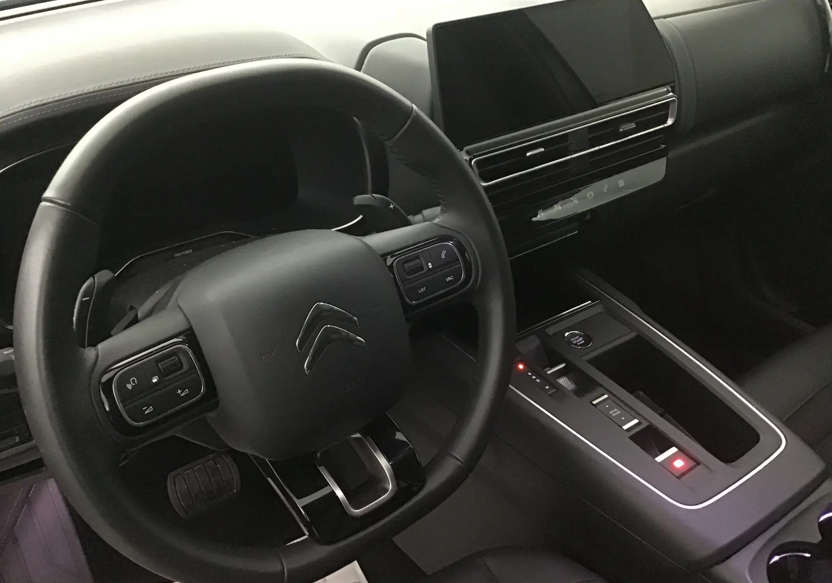 Vue rapprochée de l'intérieur noir du Citroën C5 Aircross 2024, volant cuir et écran tactile central visible.