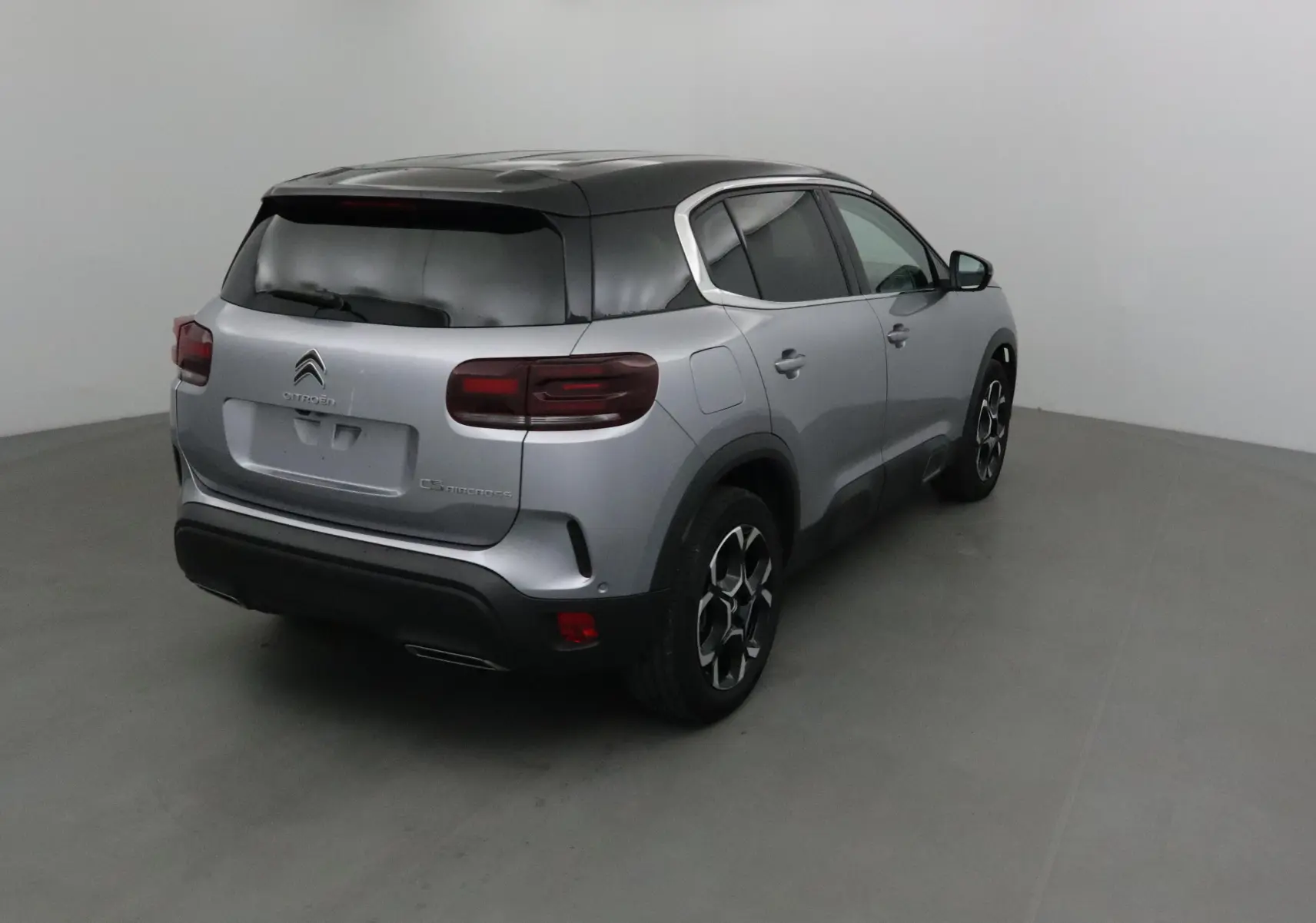 Vue 3/4 arrière droit du Citroën C5 Aircross 2024 gris Artense avec toit noir et jantes alliage distinctives.