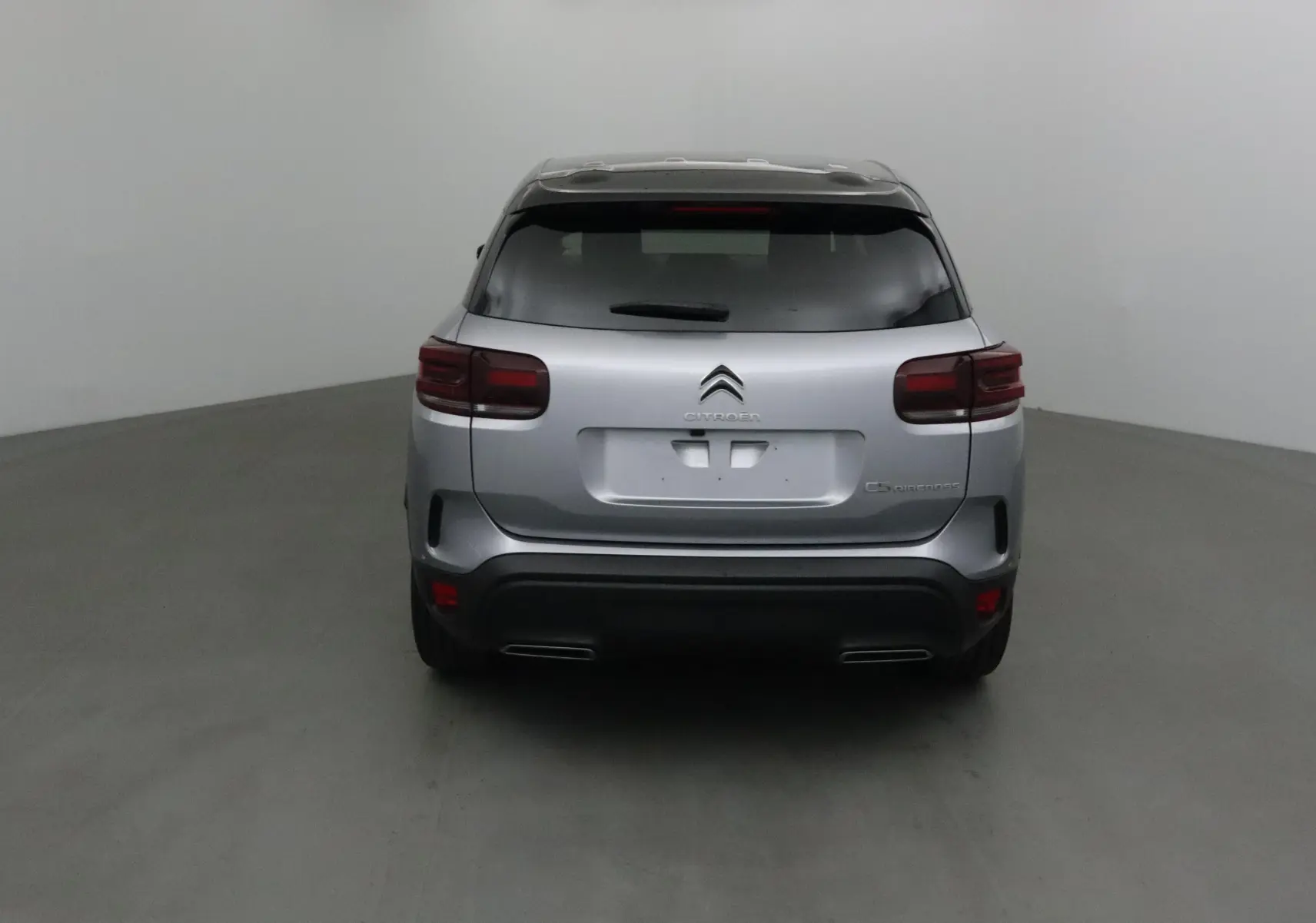 Vue arrière d'un Citroën C5 Aircross gris Artense avec toit noir, feux arrière foncés et double sortie d'échappement intégrée.