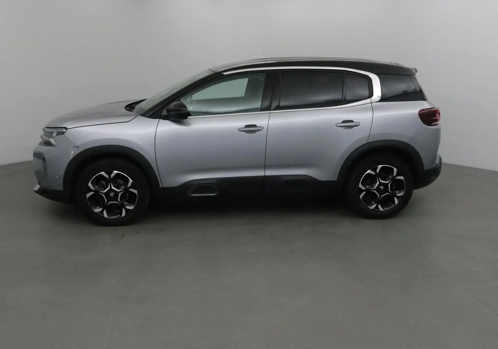 Profil côté gauche d'un Citroën C5 Aircross 2024 gris Artense avec toit noir et jantes alliage noires.