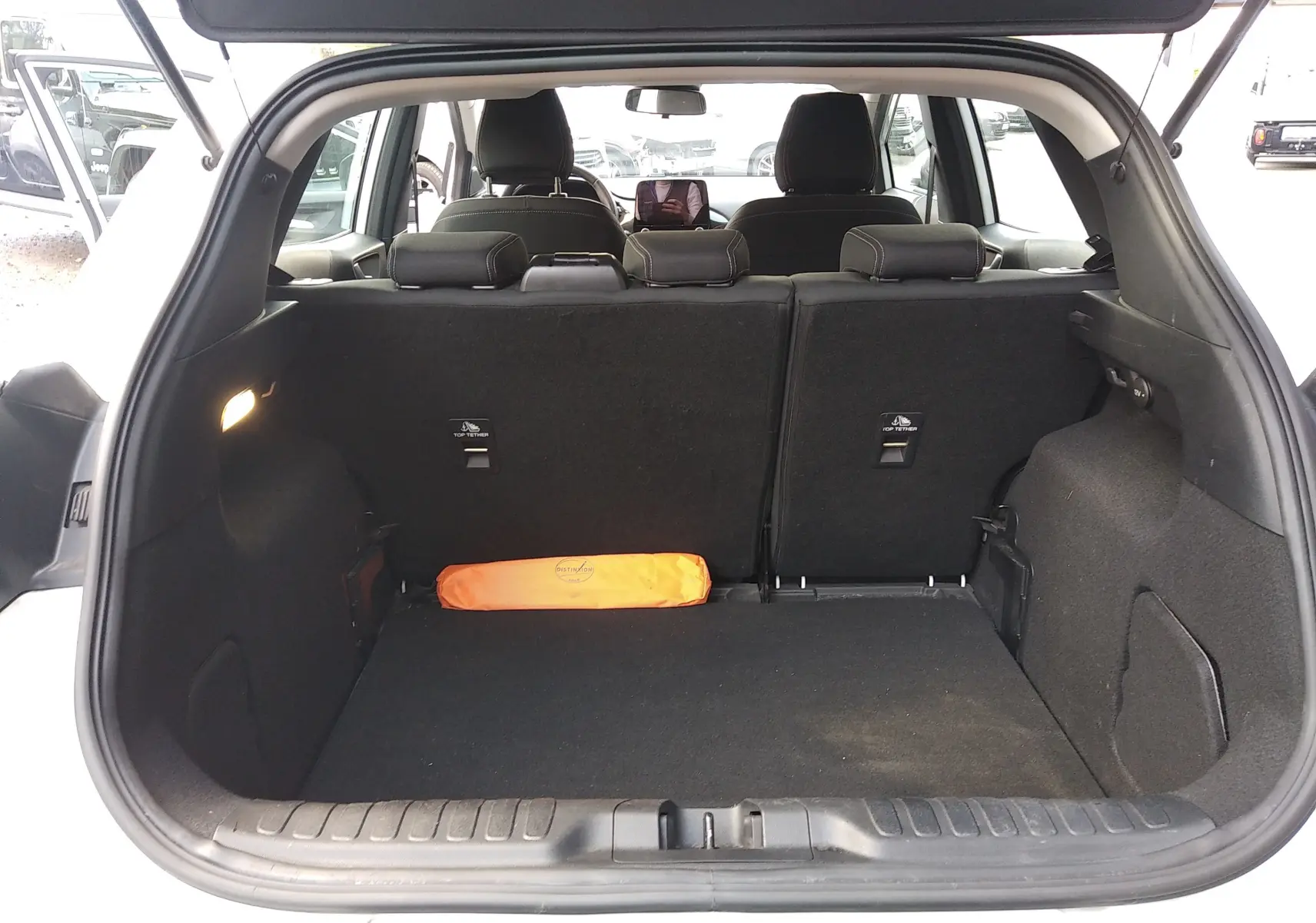 Coffre ouvert d'un Ford Puma blanc 2021, vue arrière montrant l'espace de chargement avec un triangle de signalisation orange.